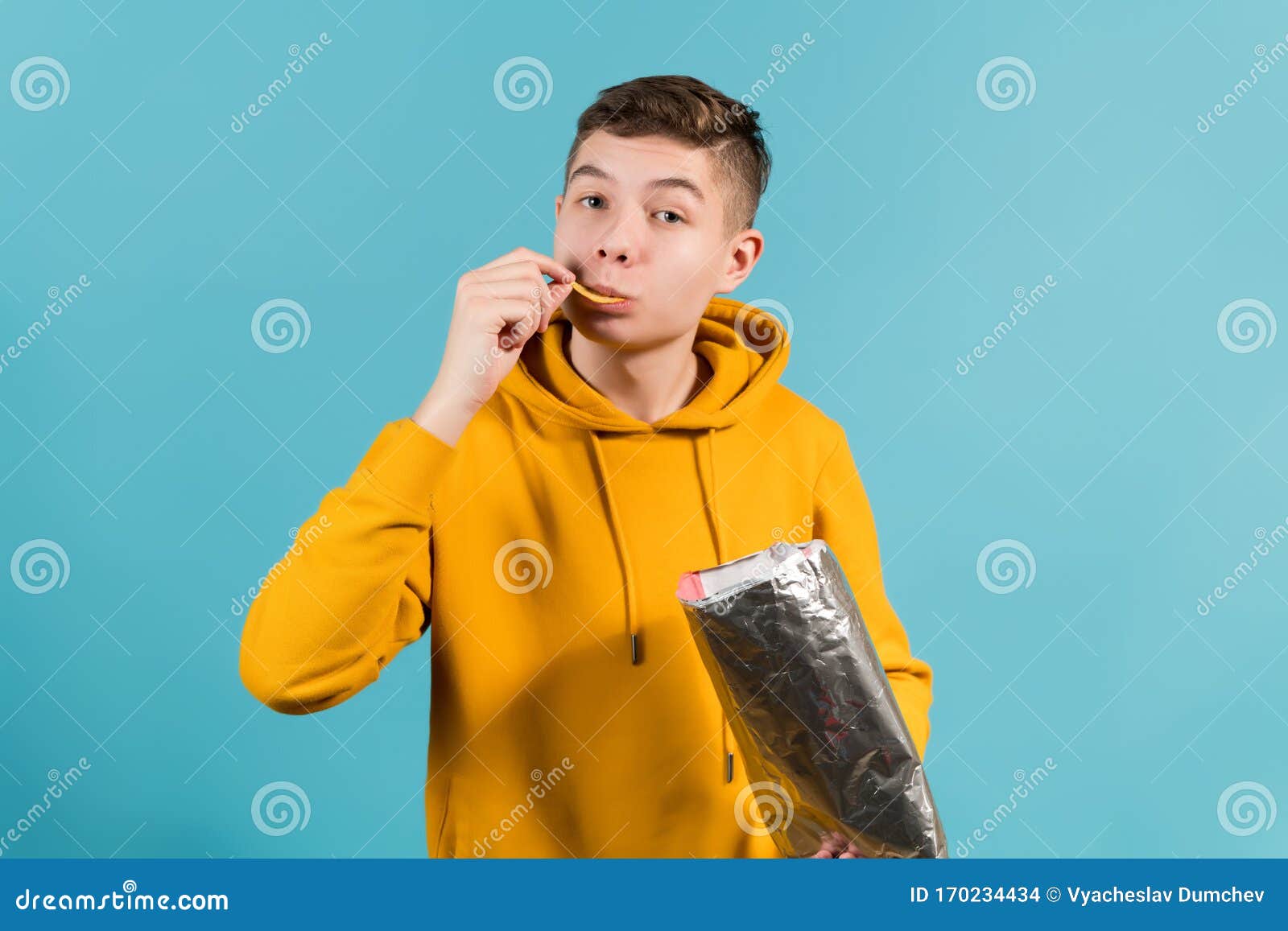 Young Guy Eating Chips on a Blue Background Stock Photo Image of