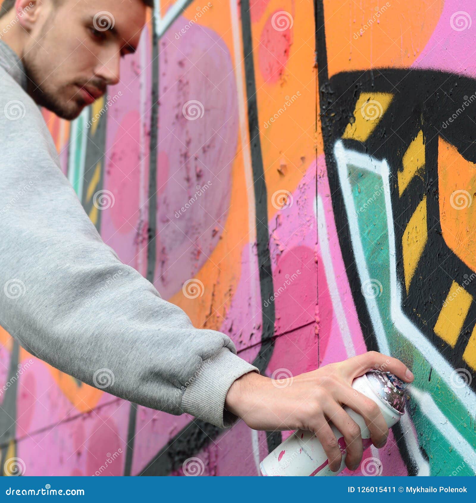 A Young Guy in a Gray Hoodie Paints Graffiti in Pink and Green C Stock ...