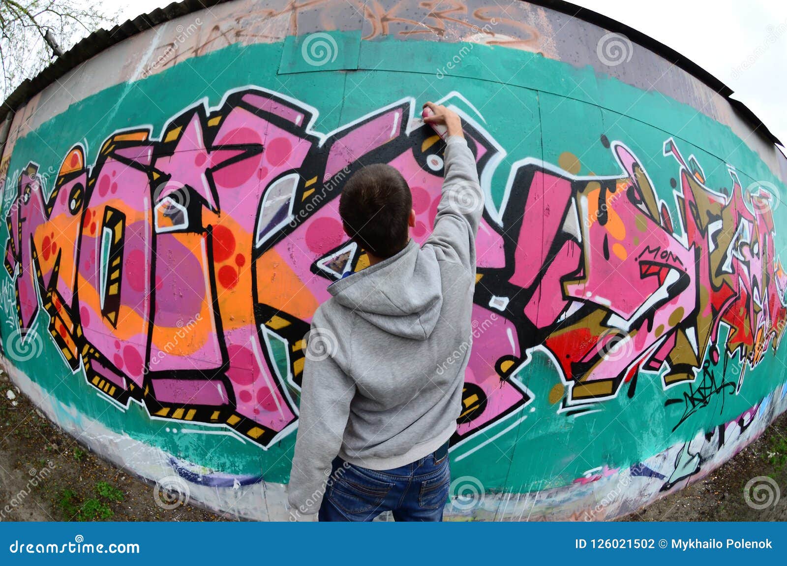 A Young Guy in a Gray Hoodie Paints Graffiti in Pink and Green C Stock ...