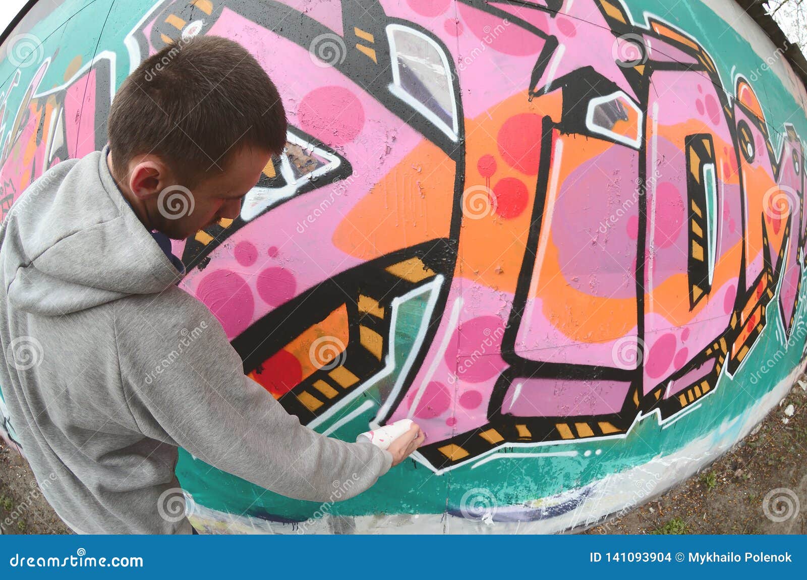 A Young Guy in a Gray Hoodie Paints Graffiti in Pink and Green C Stock ...