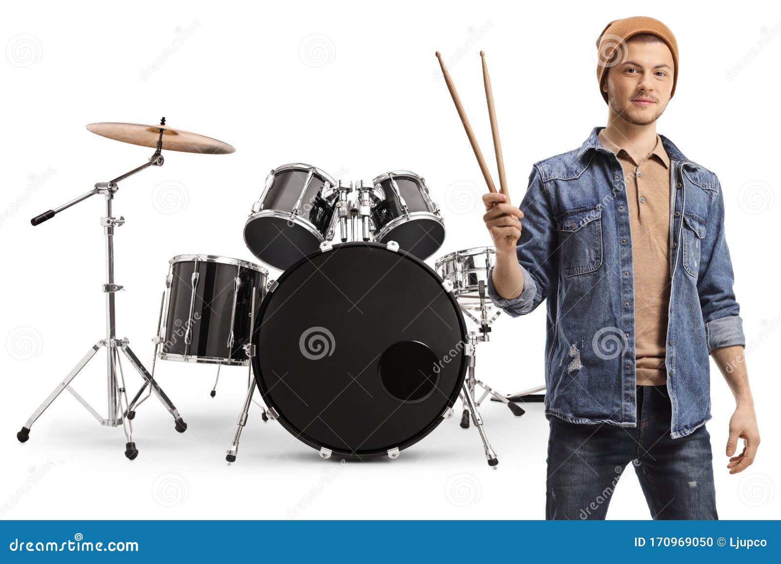 Young Guy Holding Drumsticks and Posing with a Set of Drums Stock Photo