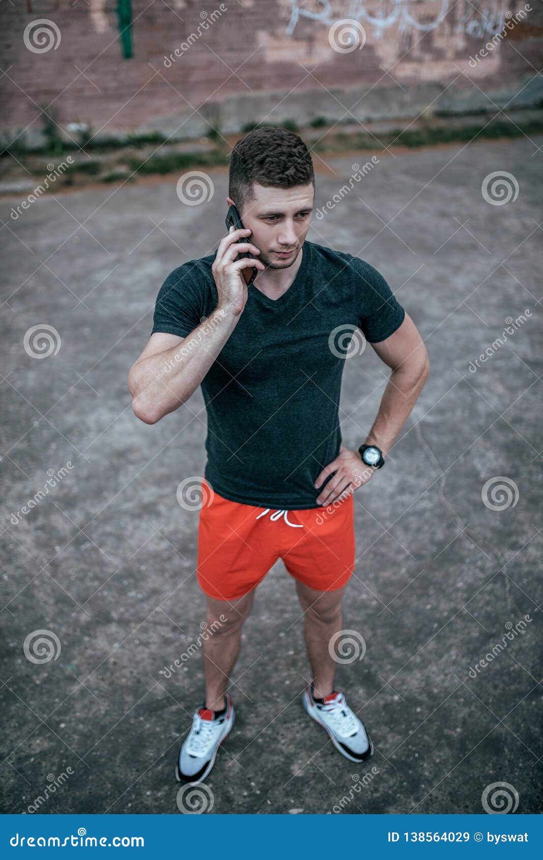 A Young Guy is Holding a Phone Ringing on a Smartphone. in the Summer ...