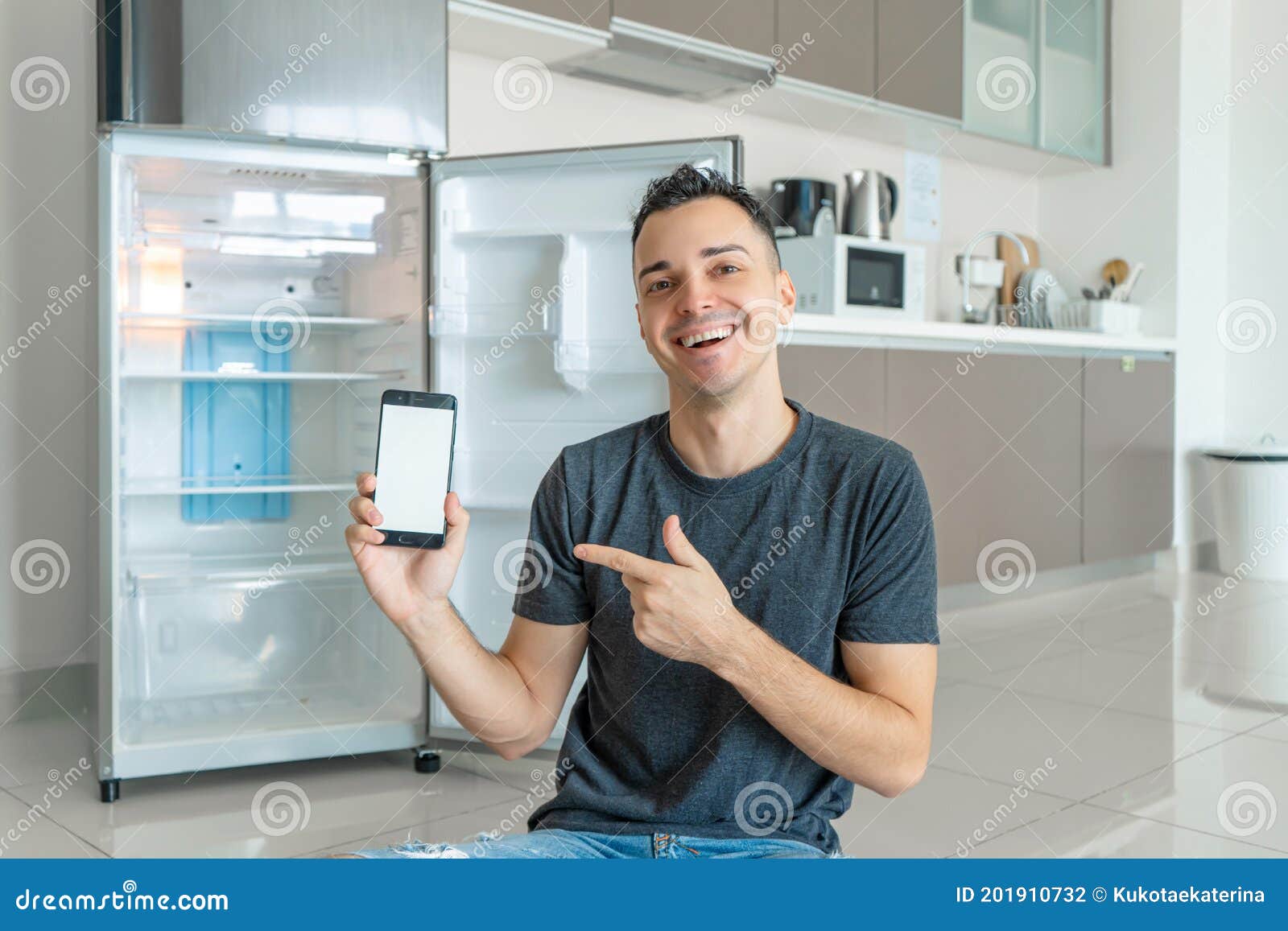 A Young Guy Orders Food Using a Smartphone. Empty Refrigerator with No