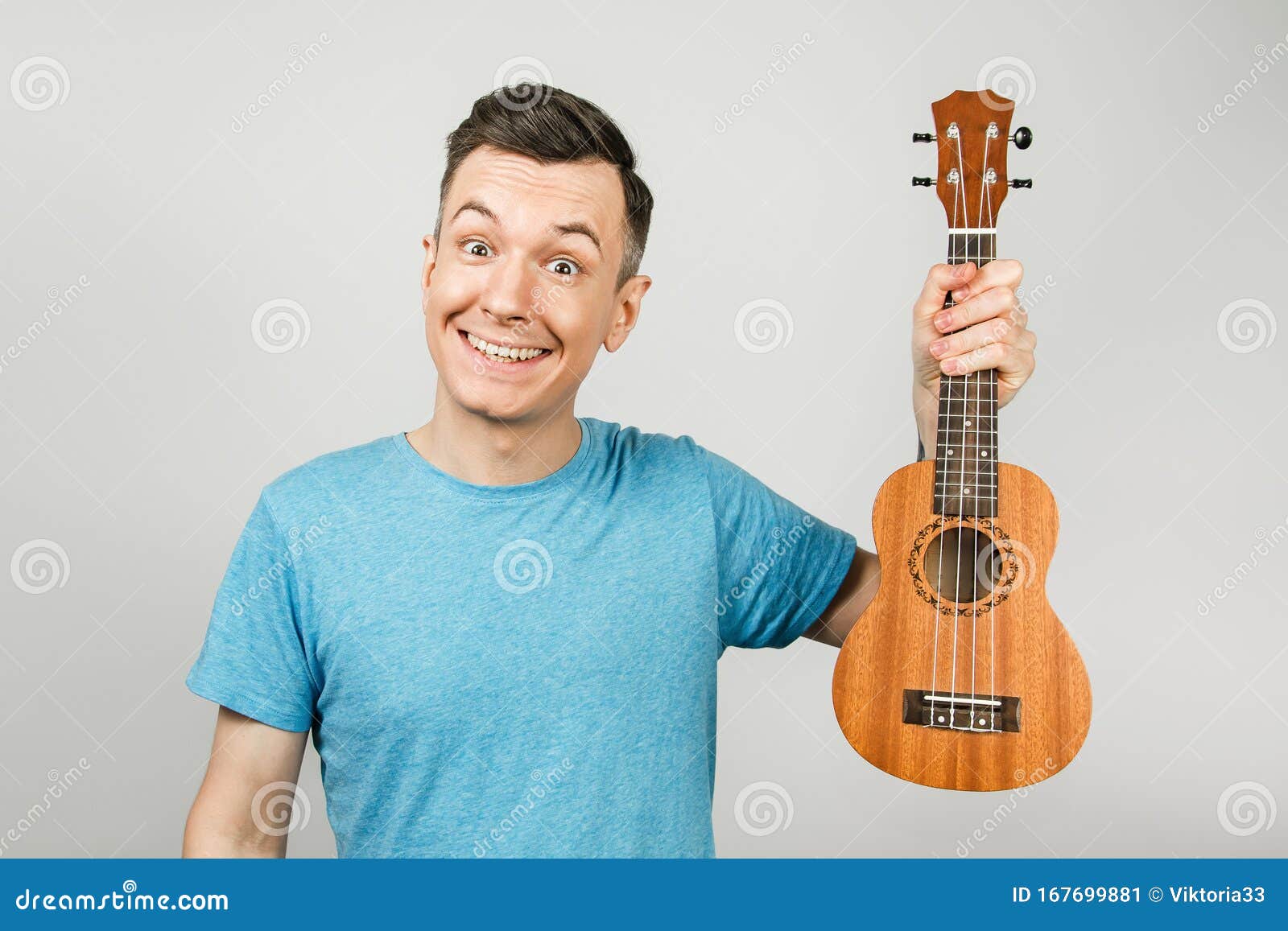 A Young Guy Plays on a Ukulele on a Light Background Stock Image