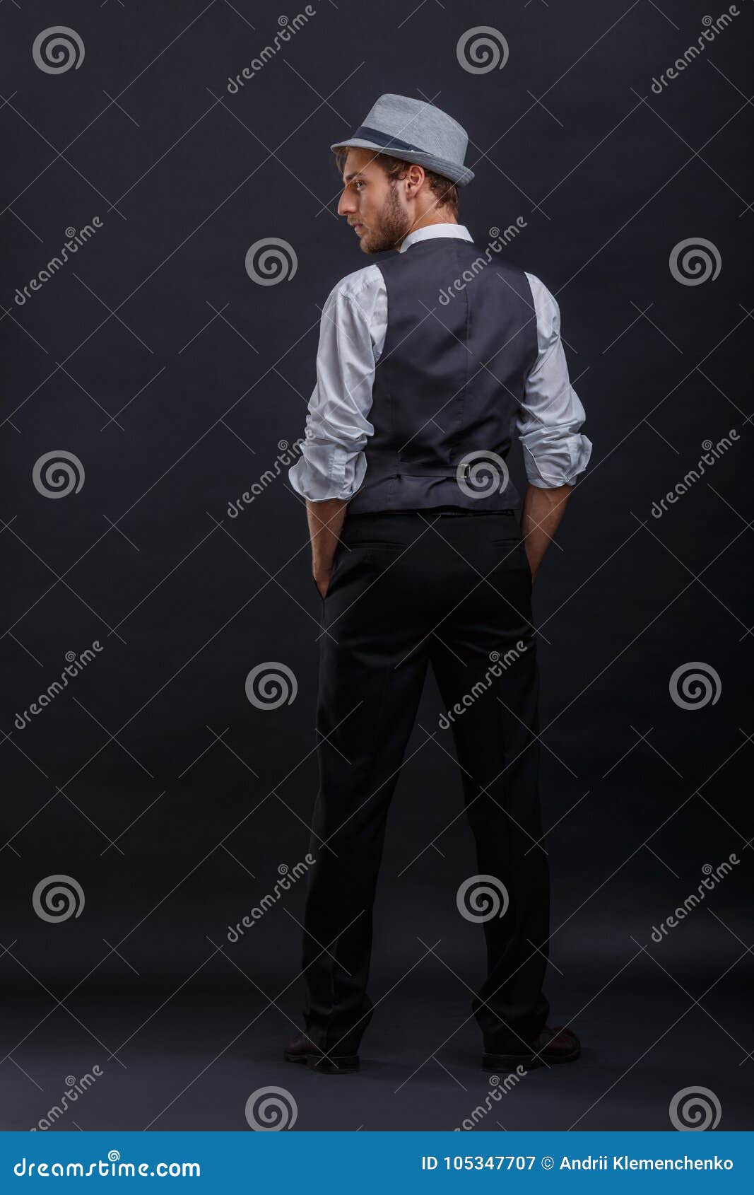Young Guy in a Retro Suit with a Vest and Hat, Stands with His Back and ...