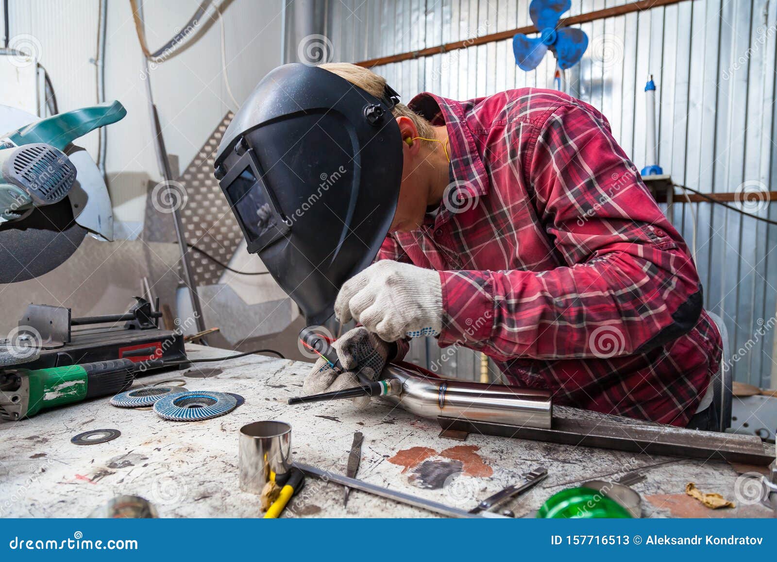 Young Guy Welder in a Checkered Red Shirt Welds a Stainless Steel Pipe ...