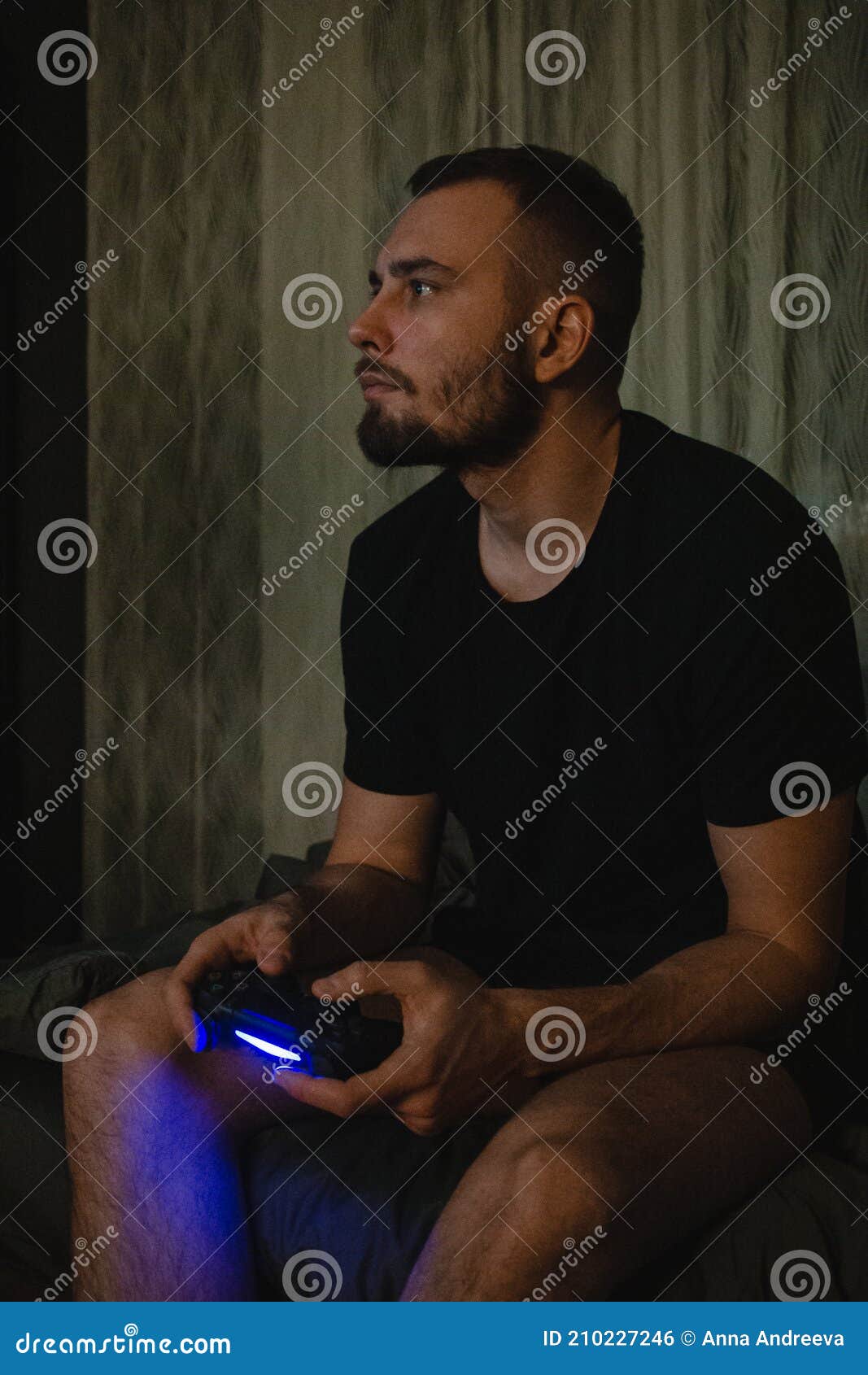 young handsome gamer man with beard in black t-shirt playing video game using joystick with a concetration on smart face thinking