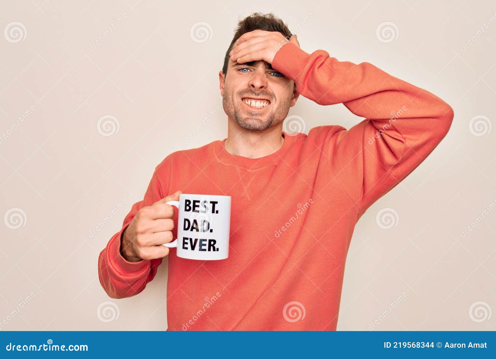 young handsome man with blue eyes drinking cup of coffe with best dad ever message stressed with hand on head, shocked with shame