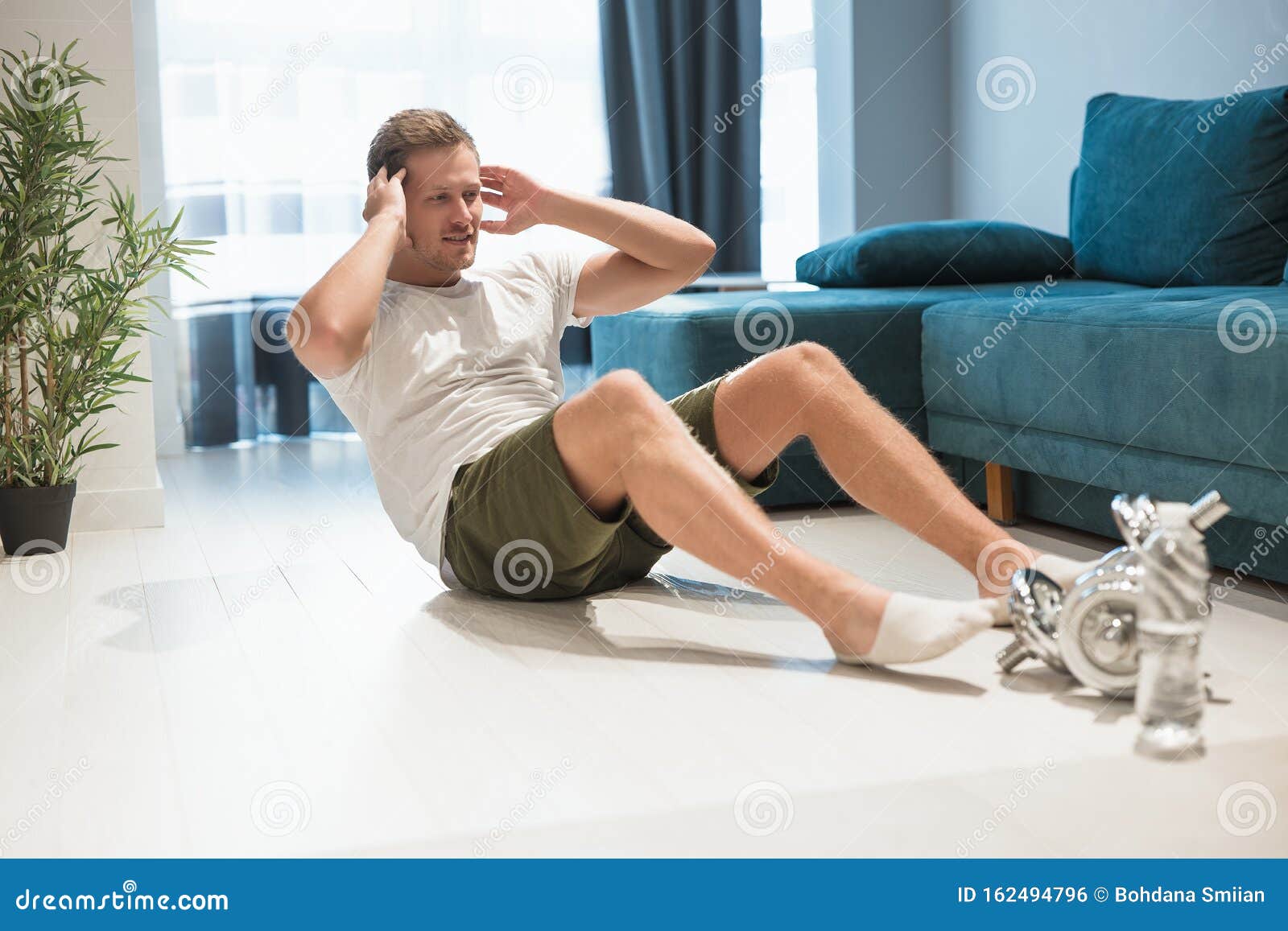 Young Handsome Man Doing Abdominal Crunches On The Floor During