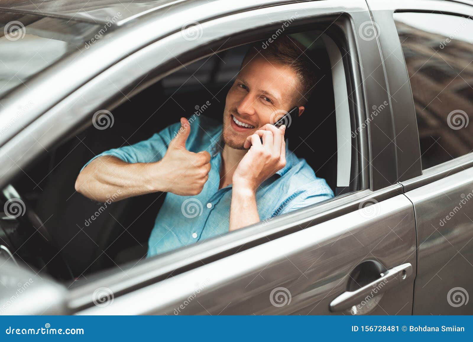 young handsome man drives unsafely having conversation on his smartphone on the run showing like sign
