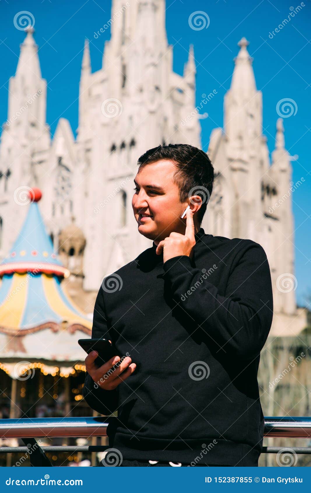 young handsome man talking via headset standing in front of tibidabo church. travel concept