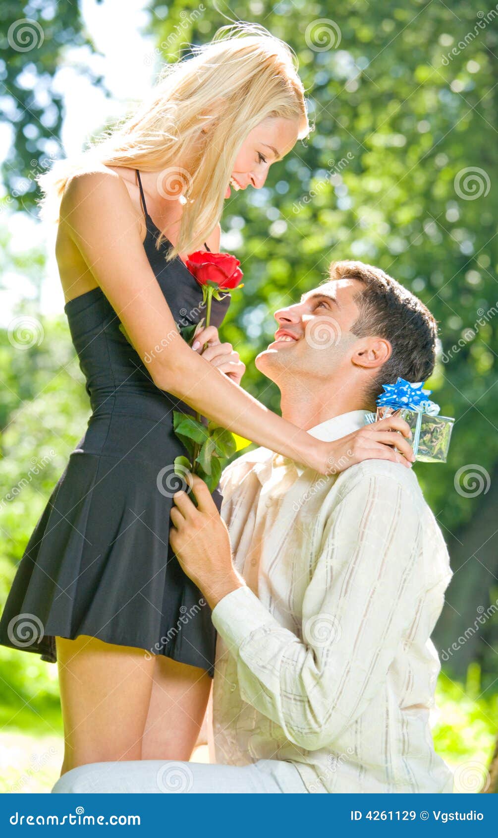 Young happy couple with rose and gift, outdoors