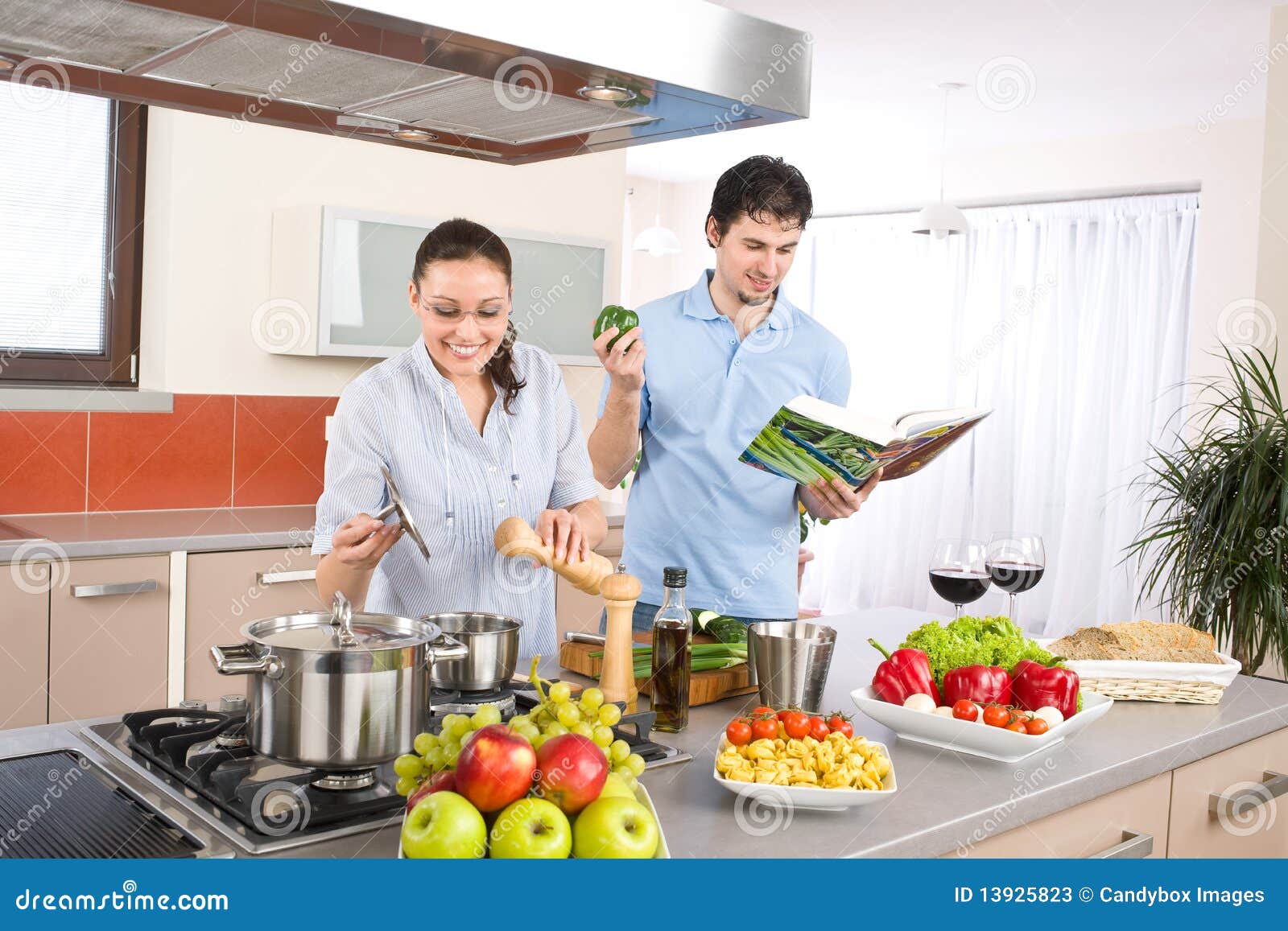 young happy couple cook in kitchen with cookbook