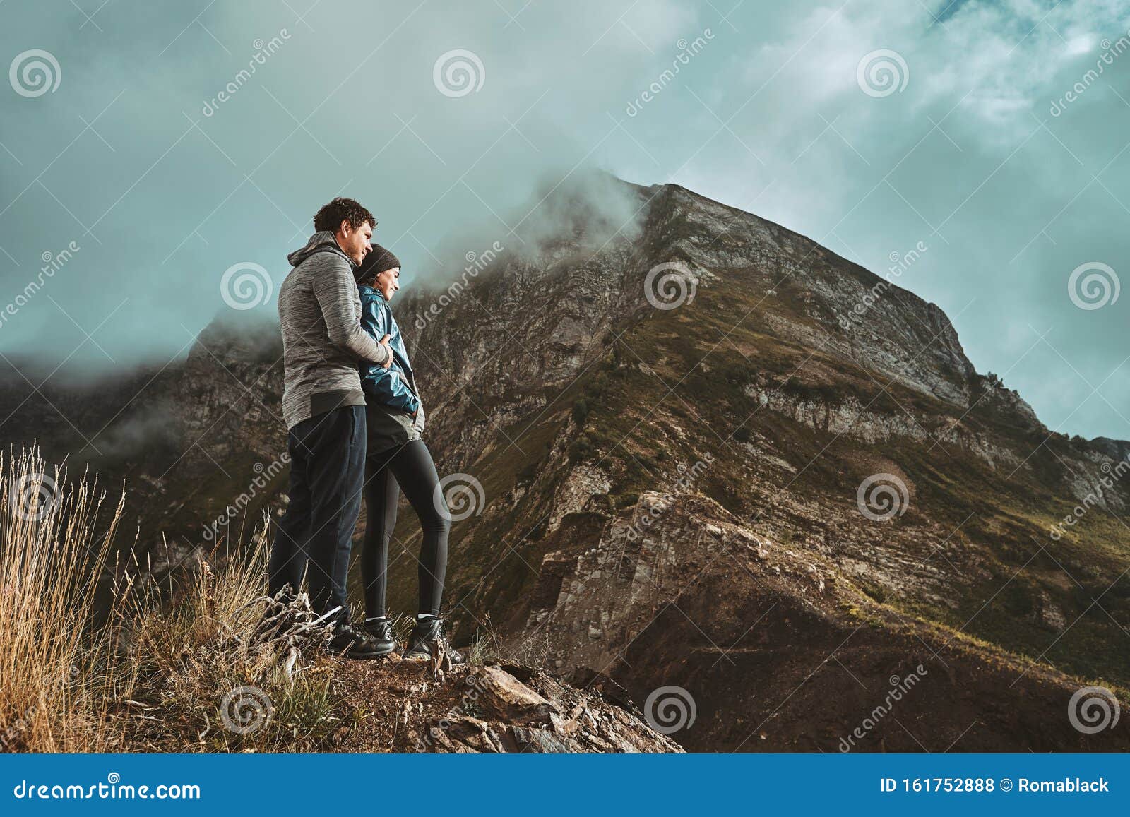 A Young, Happy Couple Hugging and Standing on a Cliff in the Mountains ...