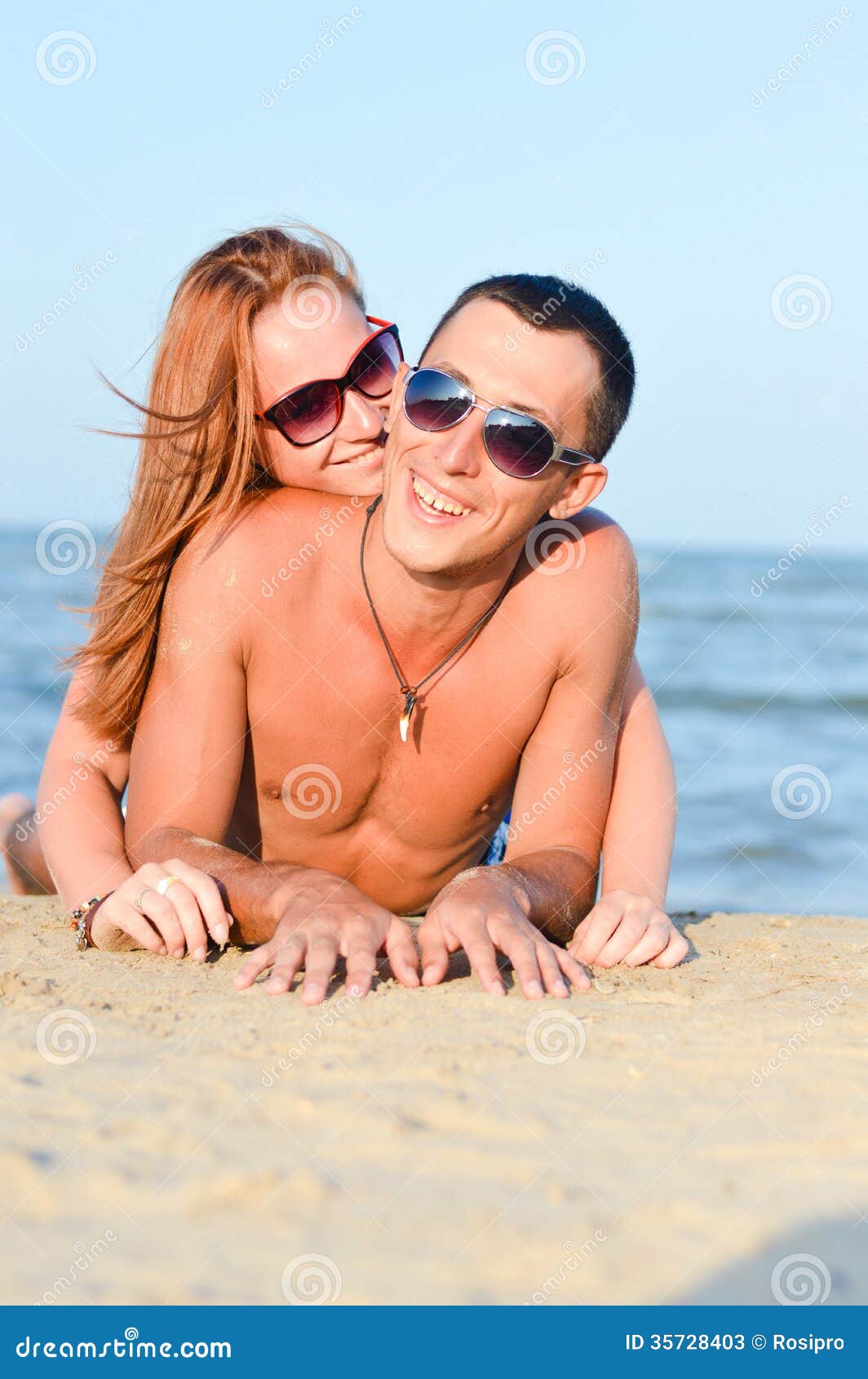 Young Happy Couple Man and Woman Lying on Sandy Beach Stock Image