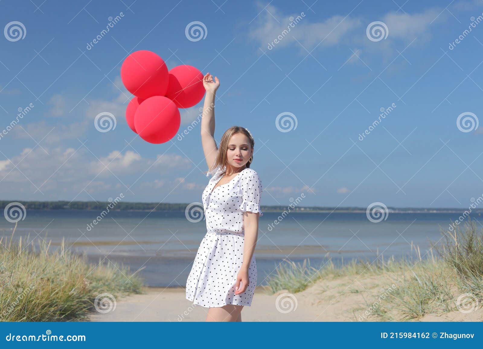 young happy girl in dress with red balloons