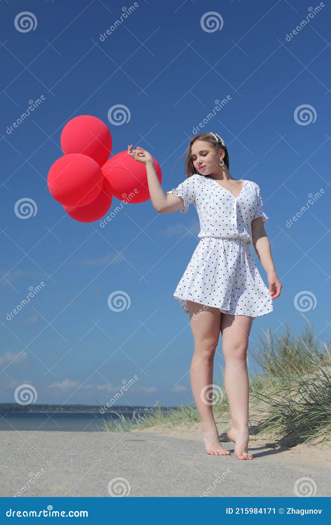 young happy girl in dress with red balloons