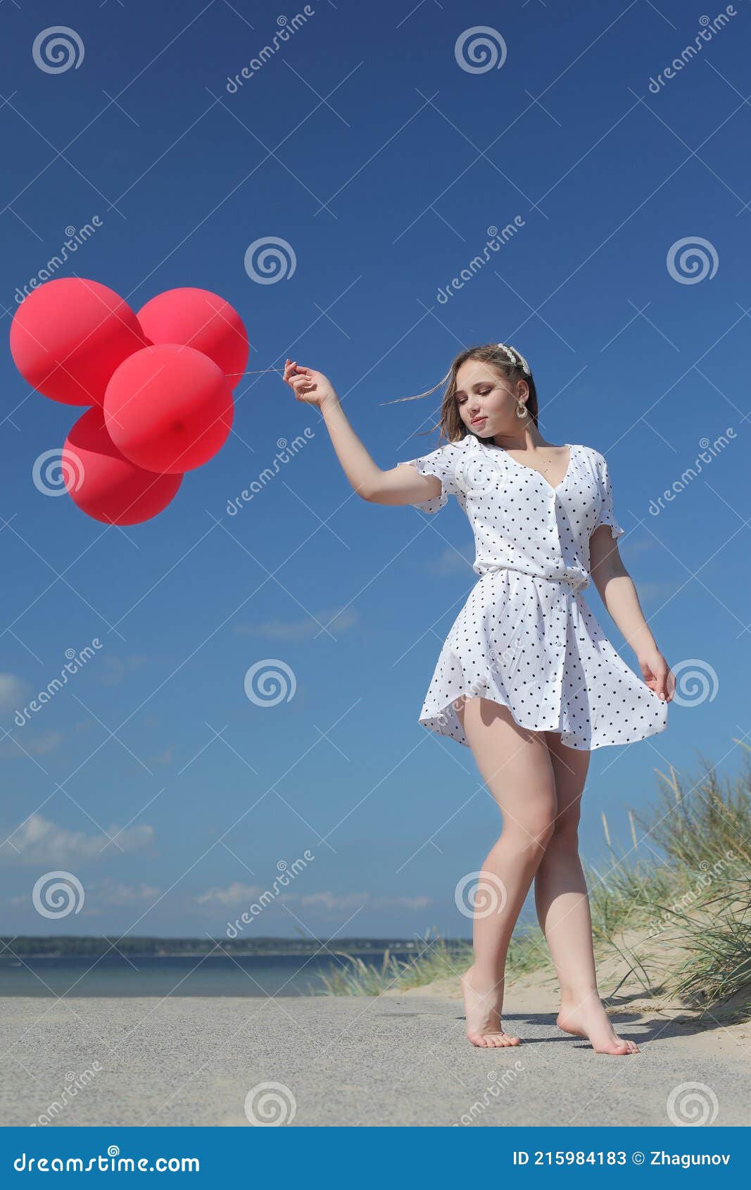 young happy girl in dress with red balloons