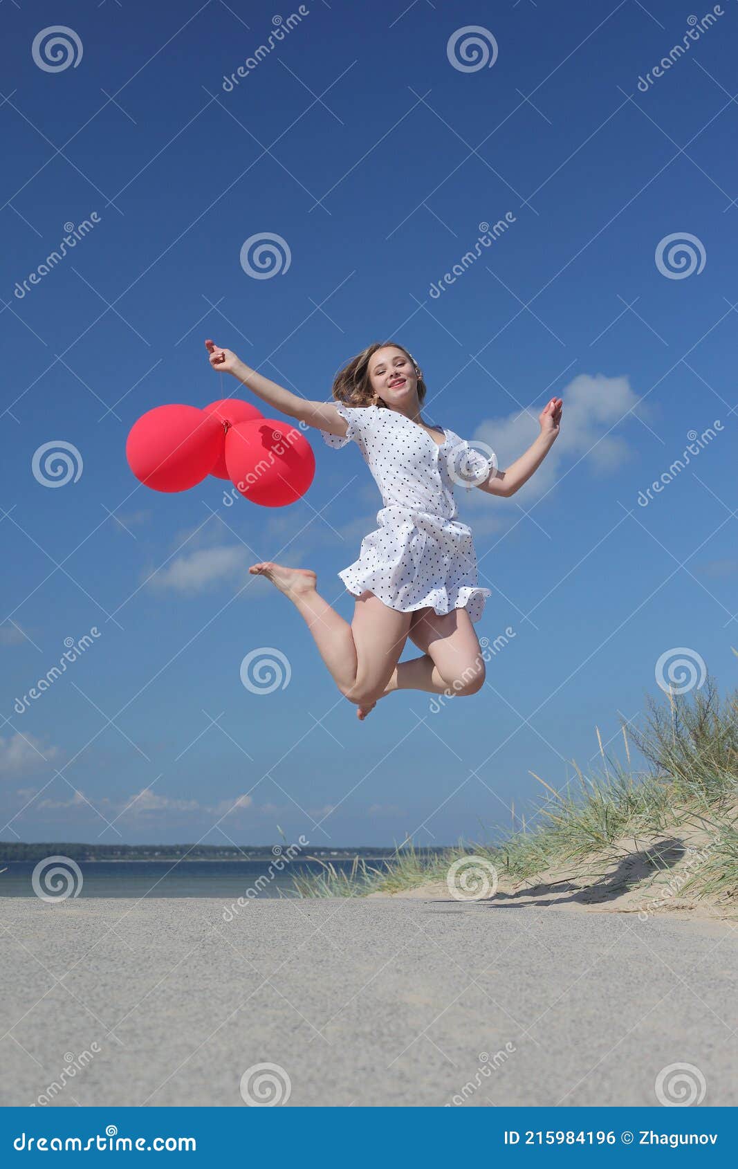young happy girl in dress with red balloons