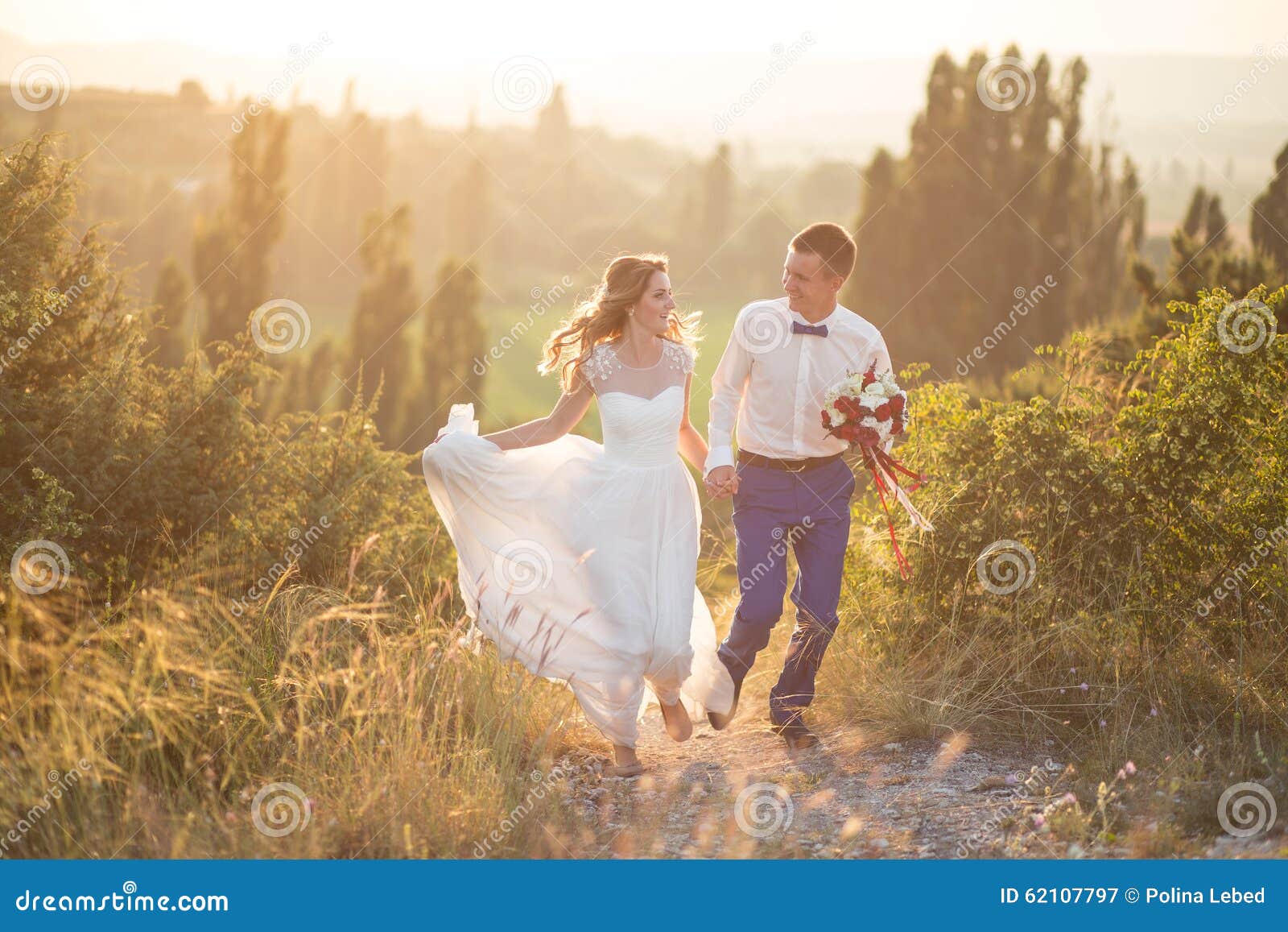 Young happy just married couple posing on the top of the mountain. Wedding day