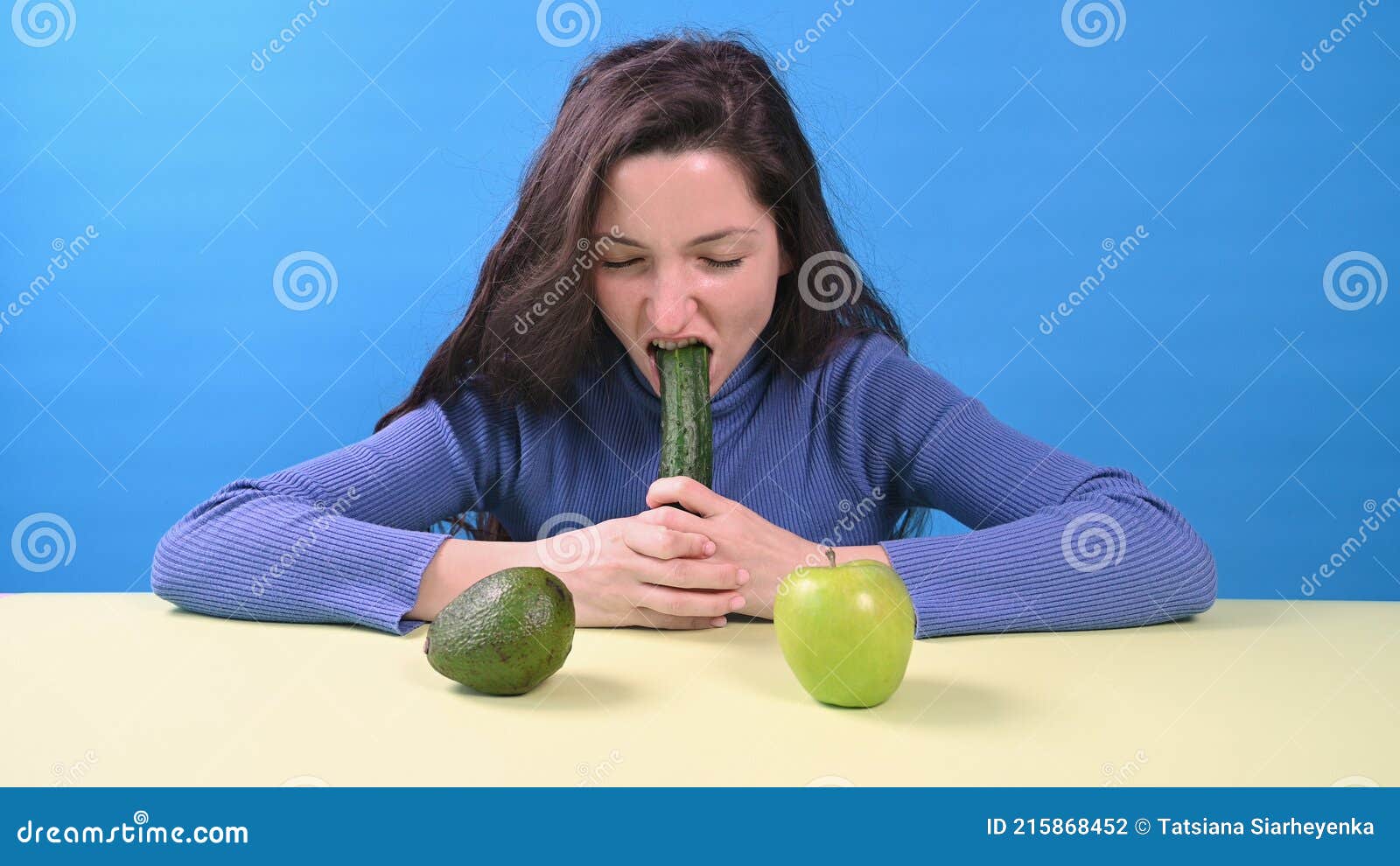 Young Happy Woman Eating Big Cucumber on Blue Background image
