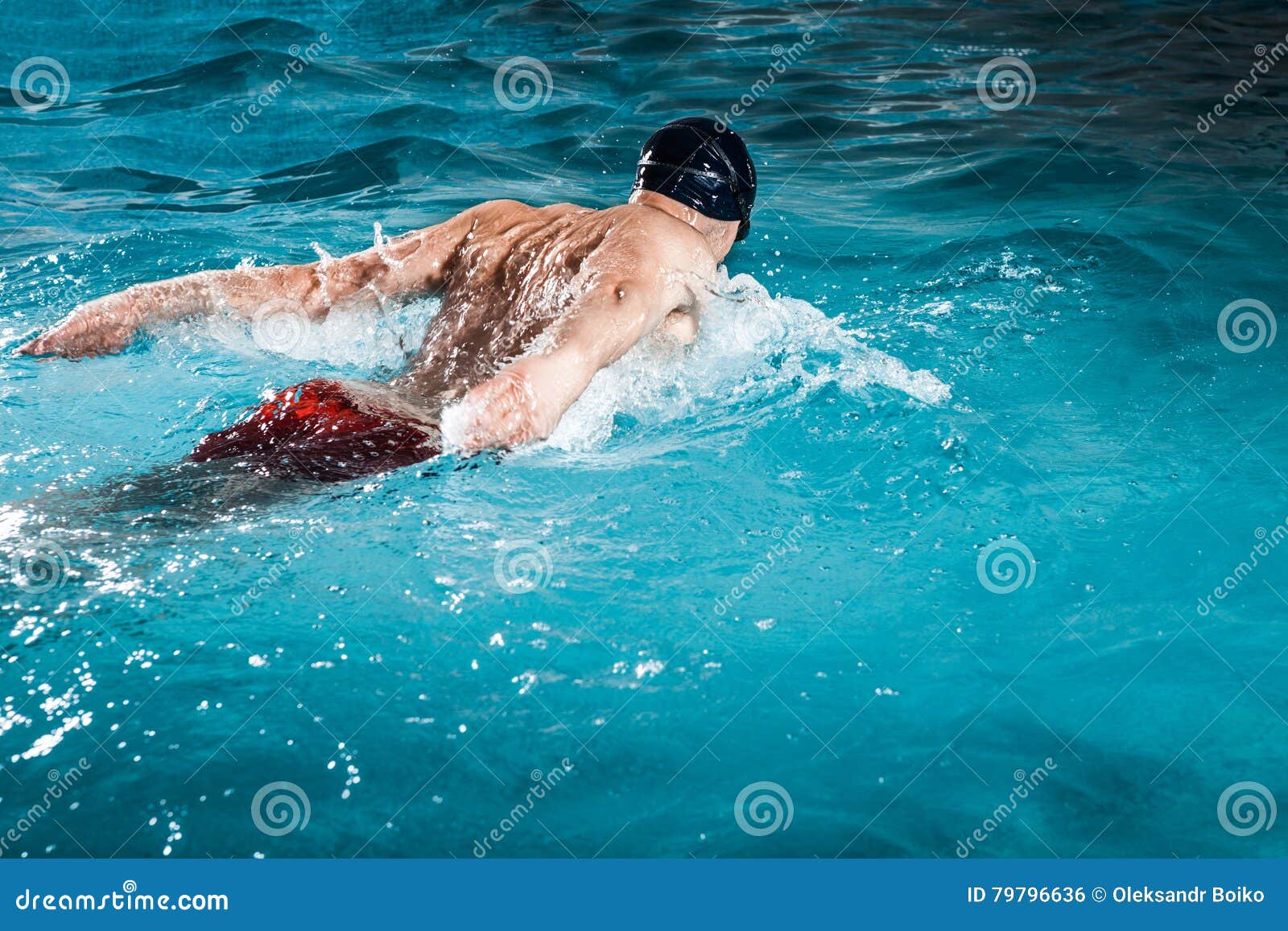 Young healthy man with muscular body swims in swimming pool