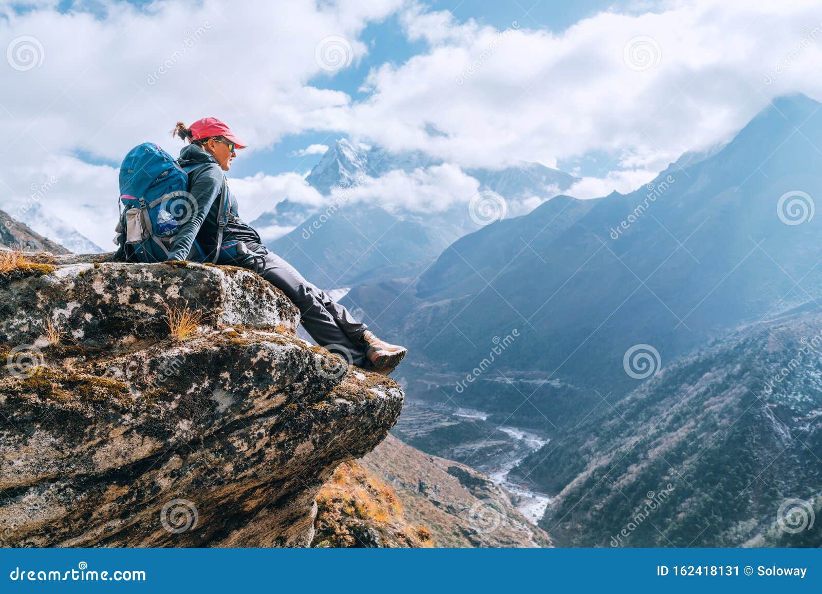 young hiker backpacker female sitting on cliff edge and enjoying the imja khola valley during high altitude everest base camp ebc