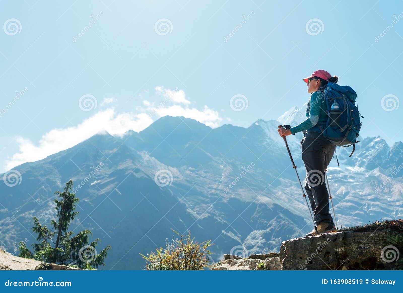 young hiker backpacker female using trekking poles enjoying mountain view during high altitude acclimatization walk. everest base