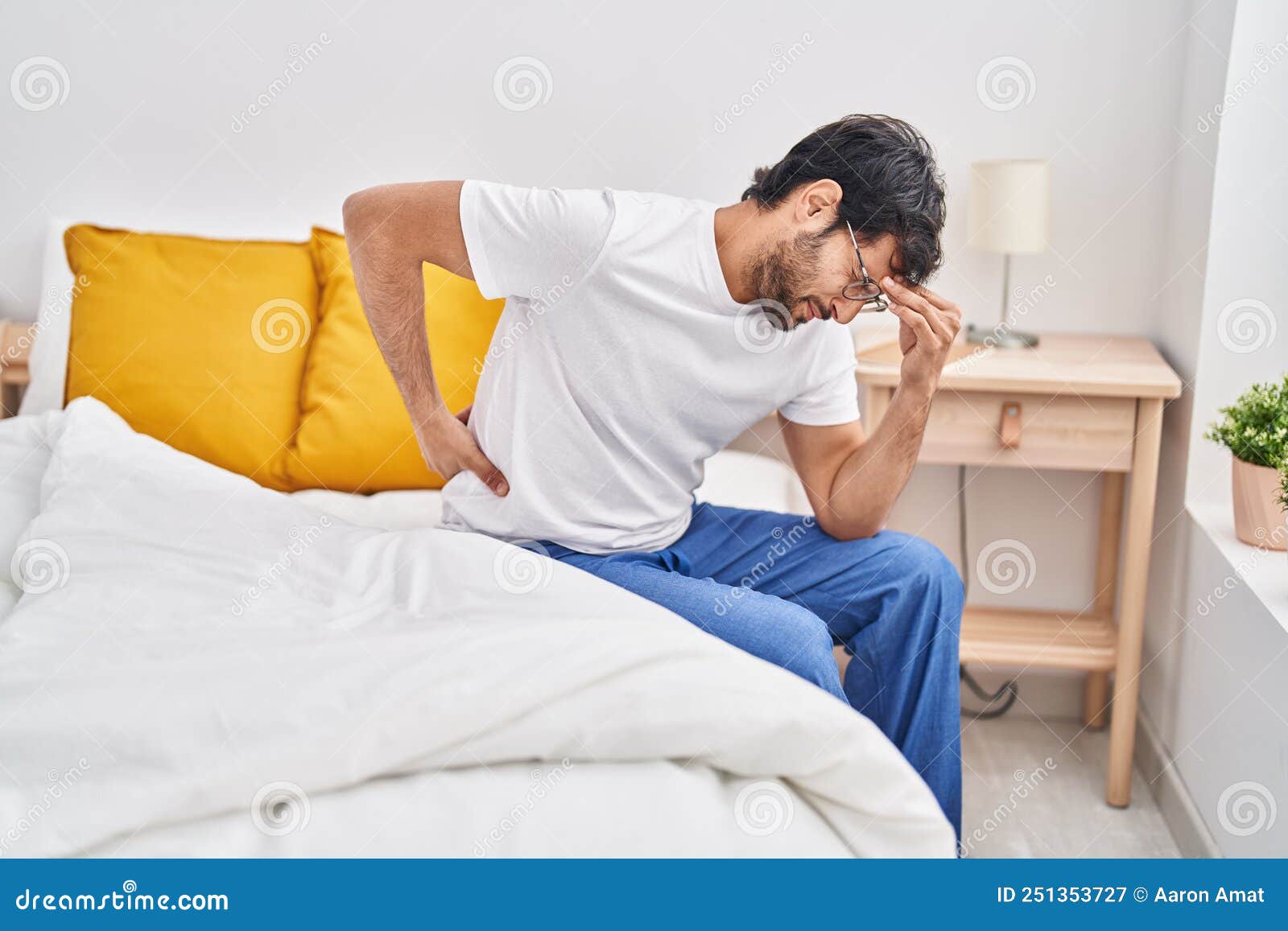 Young Hispanic Man Suffering for Back Ache Sitting on Bed at Bedroom