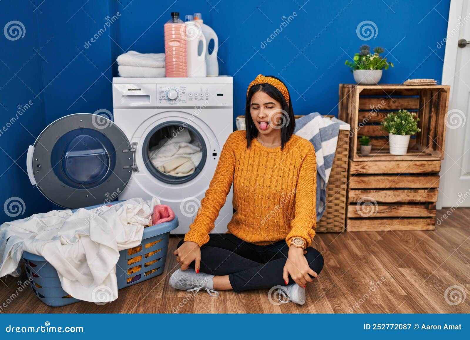 Young Hispanic Woman Doing Laundry Sticking Tongue Out Happy With Funny 