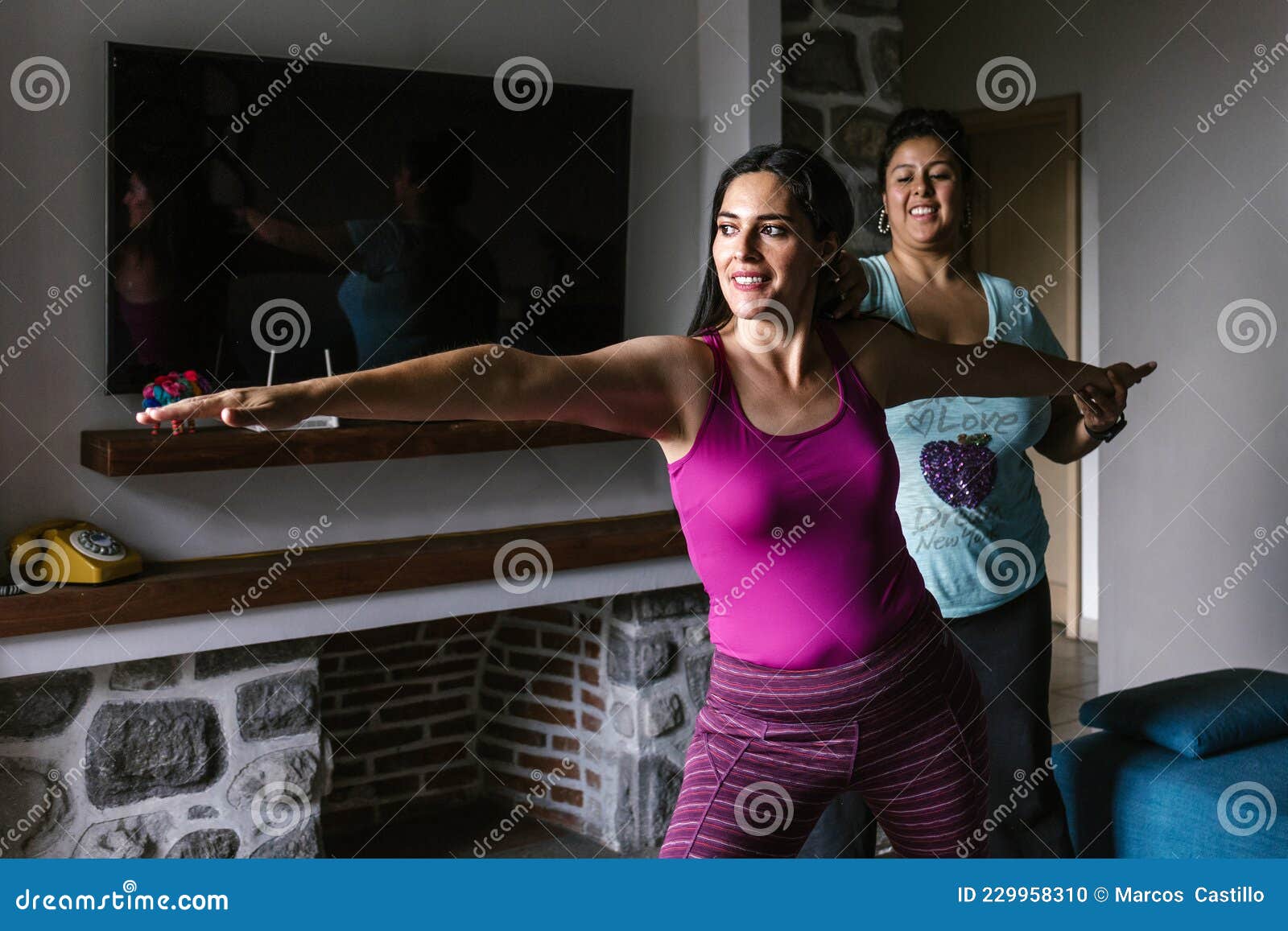 Woman in black workout clothes adjusting reformer bed in a pilates