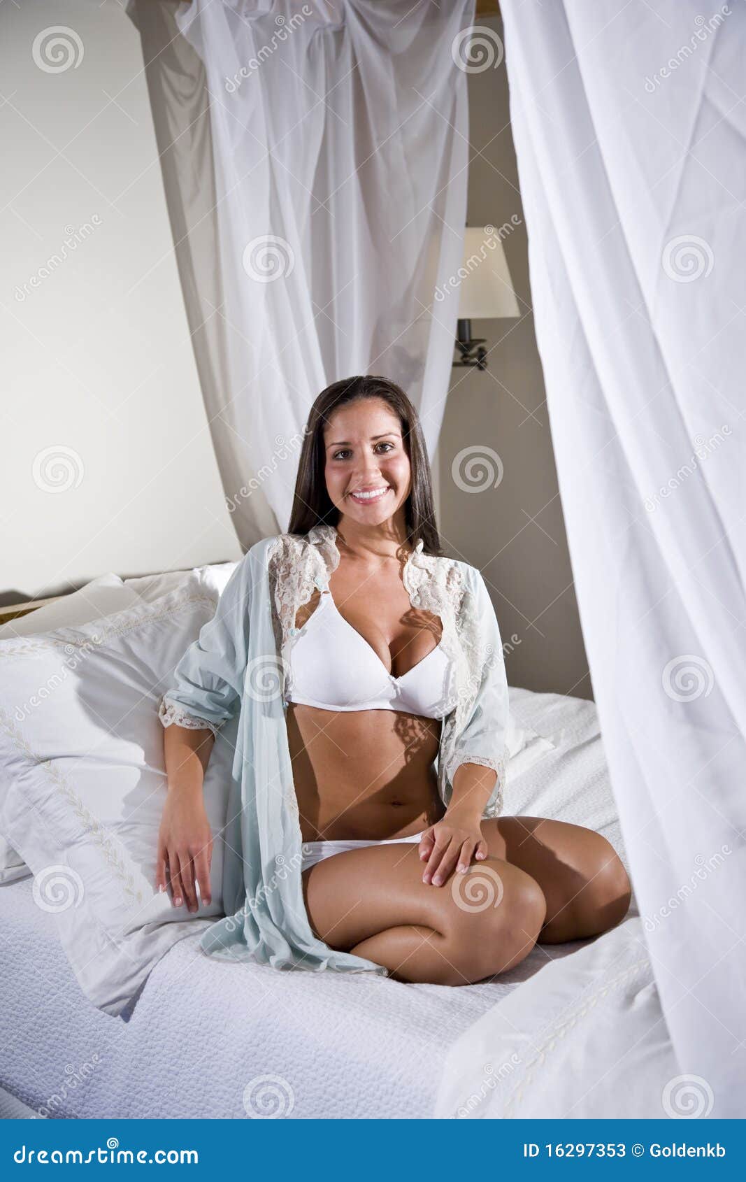 Young Hispanic Woman Sitting On White Bed Canopy