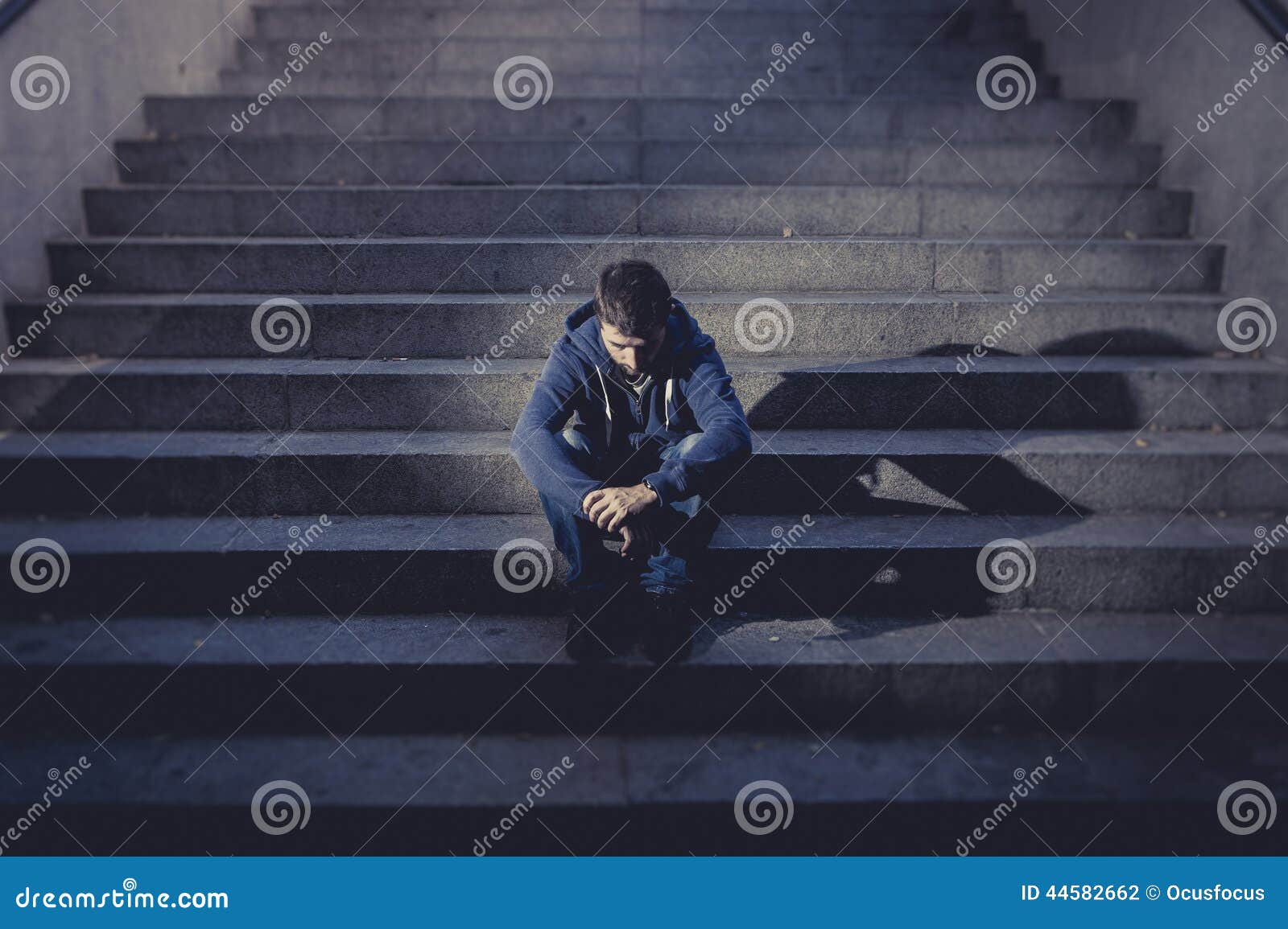 young homeless man lost in depression sitting on ground street concrete stairs