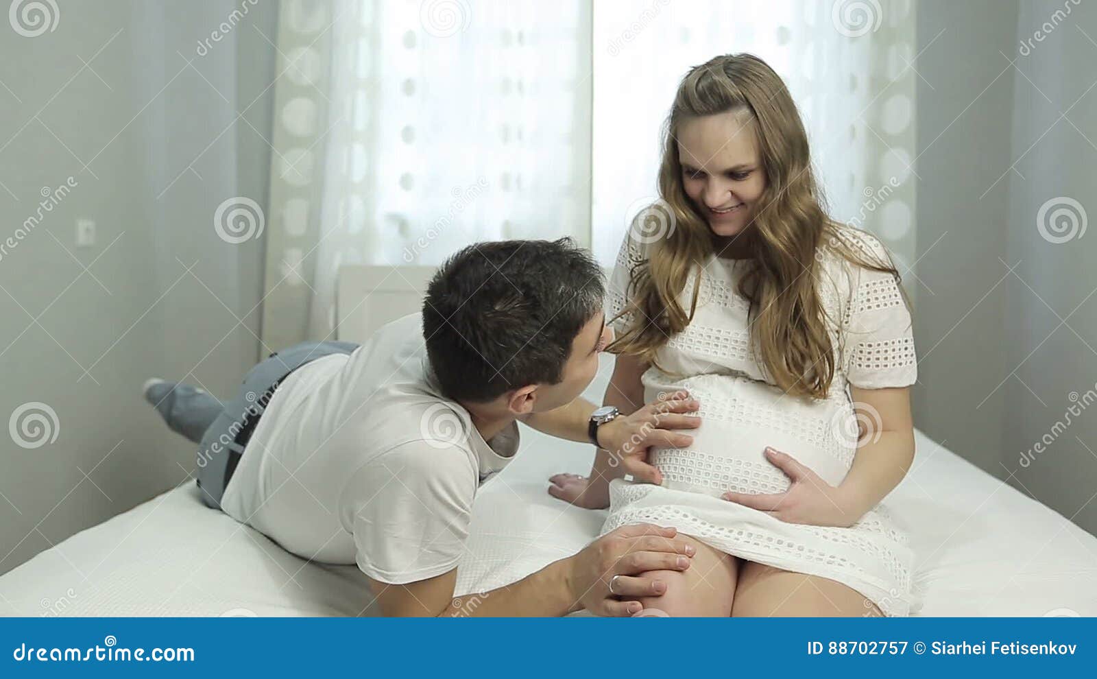 Young Husband Kissing and Stroking the Belly of His Pregnant Wife