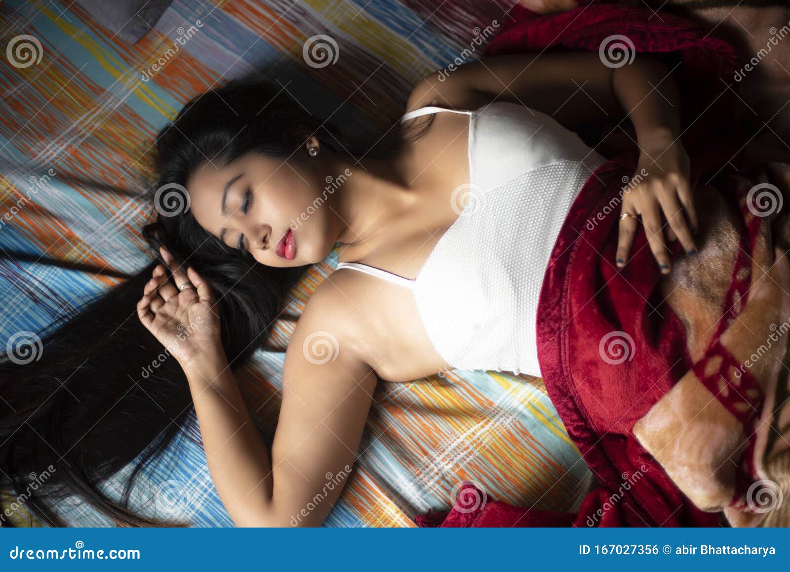 Young Indian Brunette Woman in Sleeping Wear Lying on a Bed Stock Photo photo