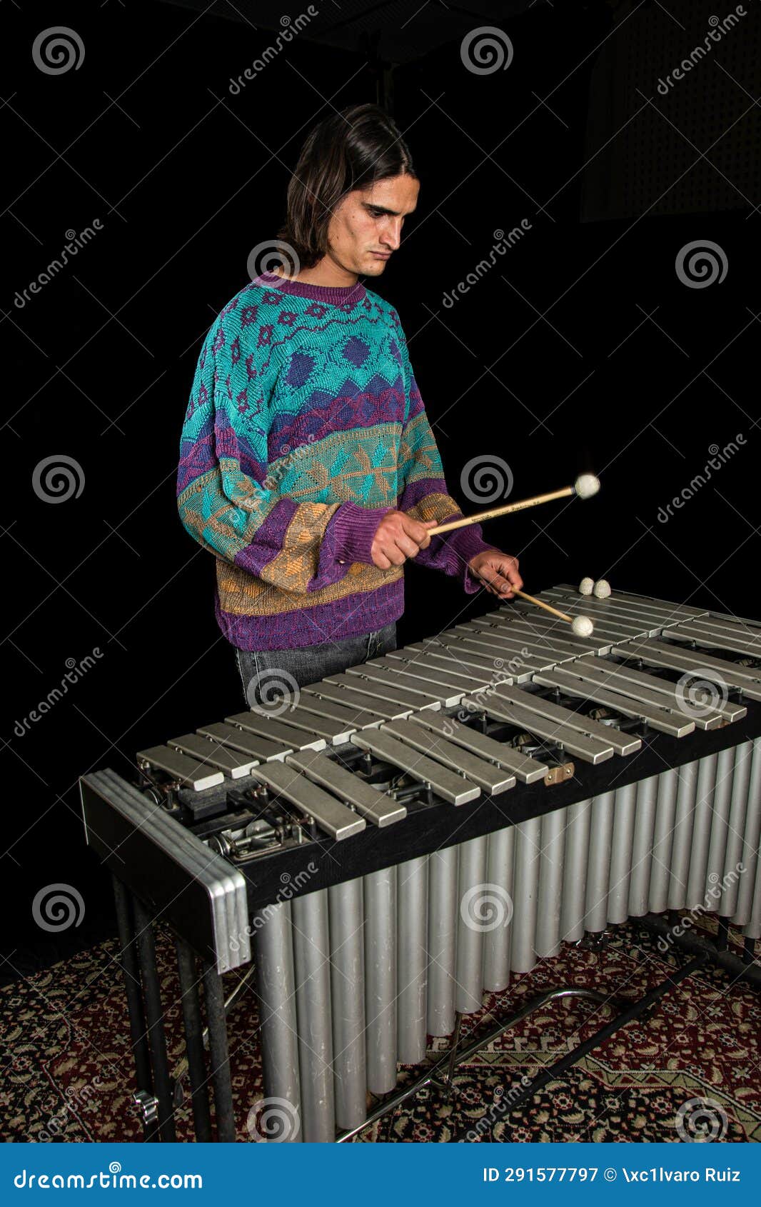 young jazz musician playing the vibraphone in his private rehearsal room. black background.