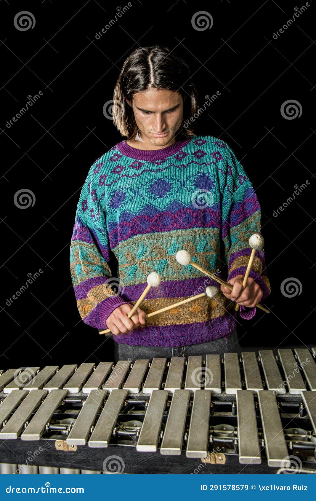 young jazz musician playing the vibraphone in his private rehearsal room. black background.