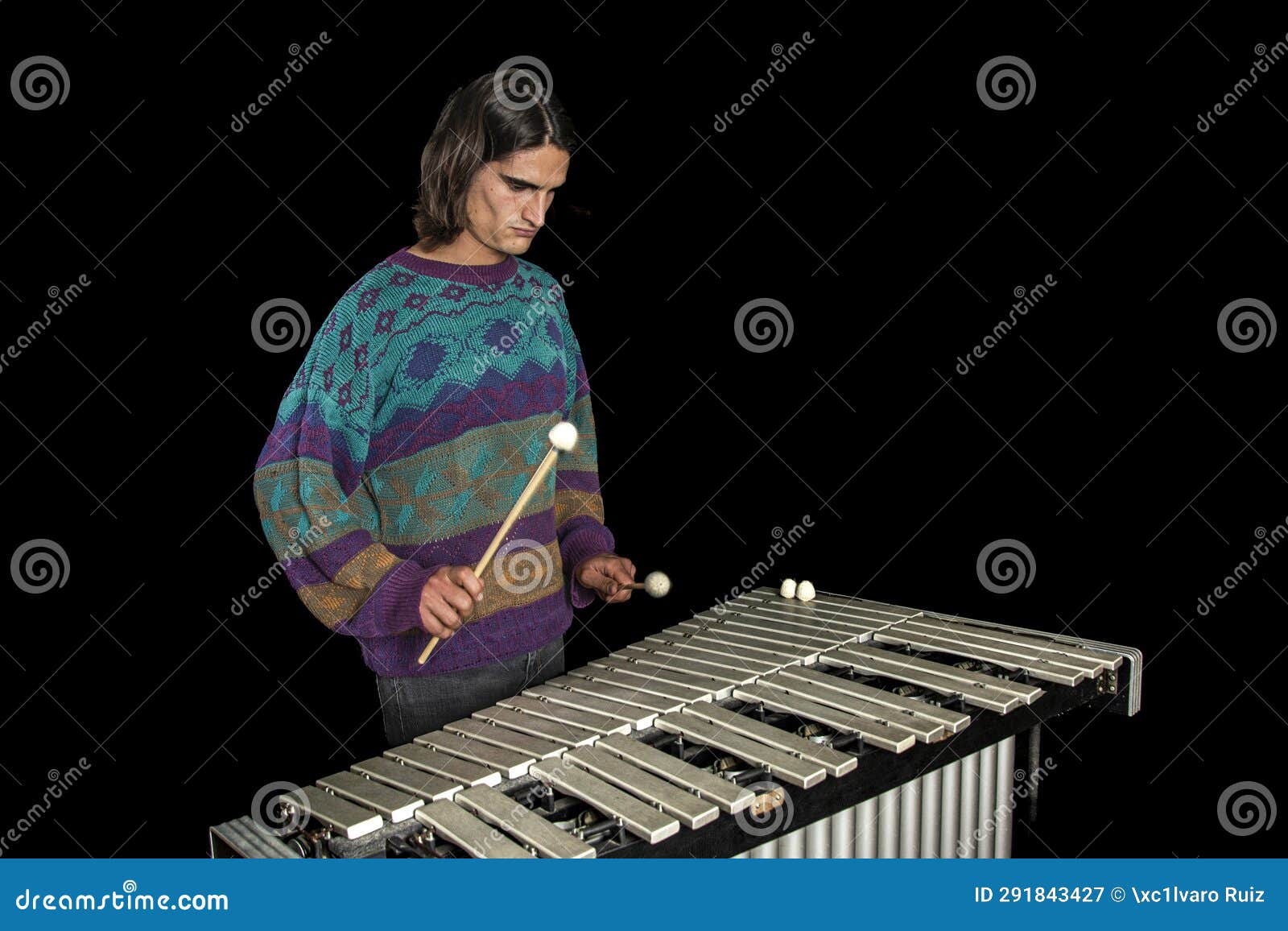 young jazz musician playing the vibraphone in his private rehearsal room. black background.