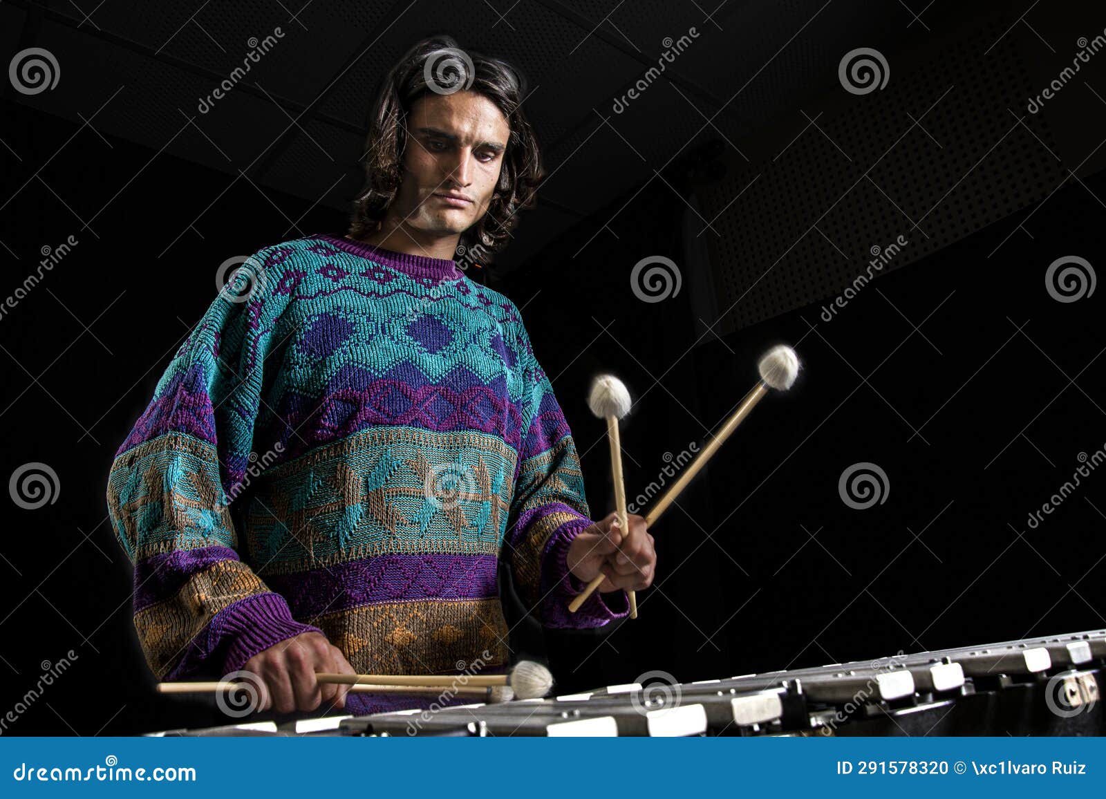 young jazz musician playing the vibraphone in his private rehearsal room. black background.