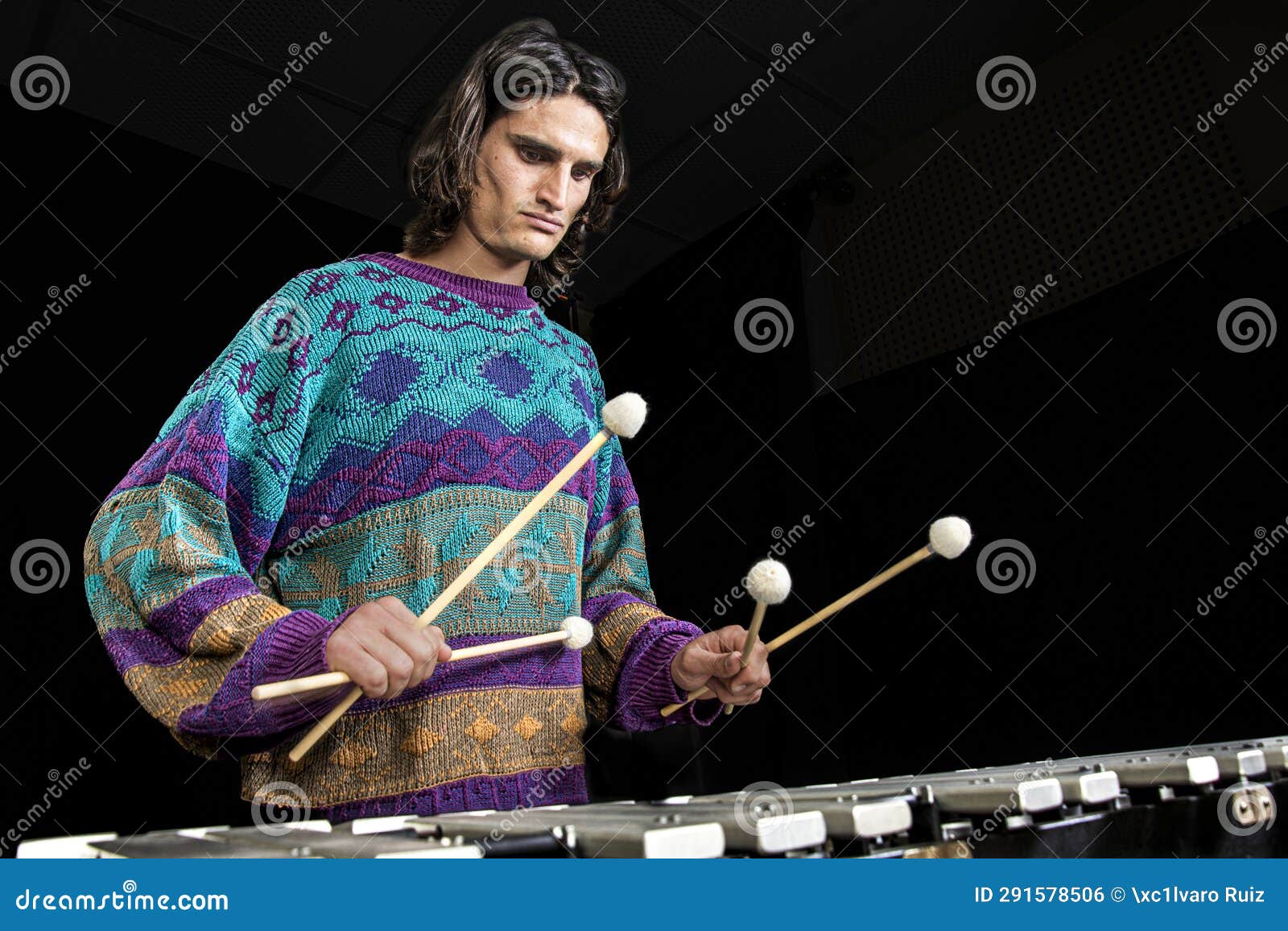 young jazz musician playing the vibraphone in his private rehearsal room. black background.