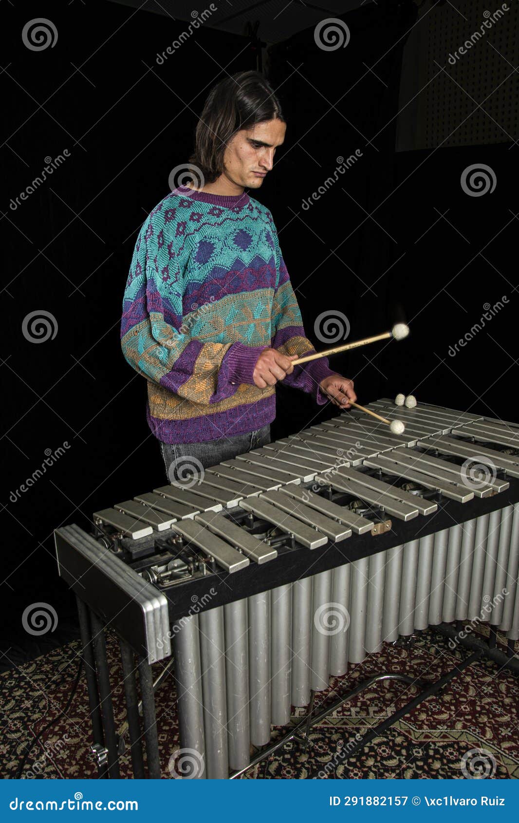 young jazz musician playing the vibraphone in his private rehearsal room. black background.