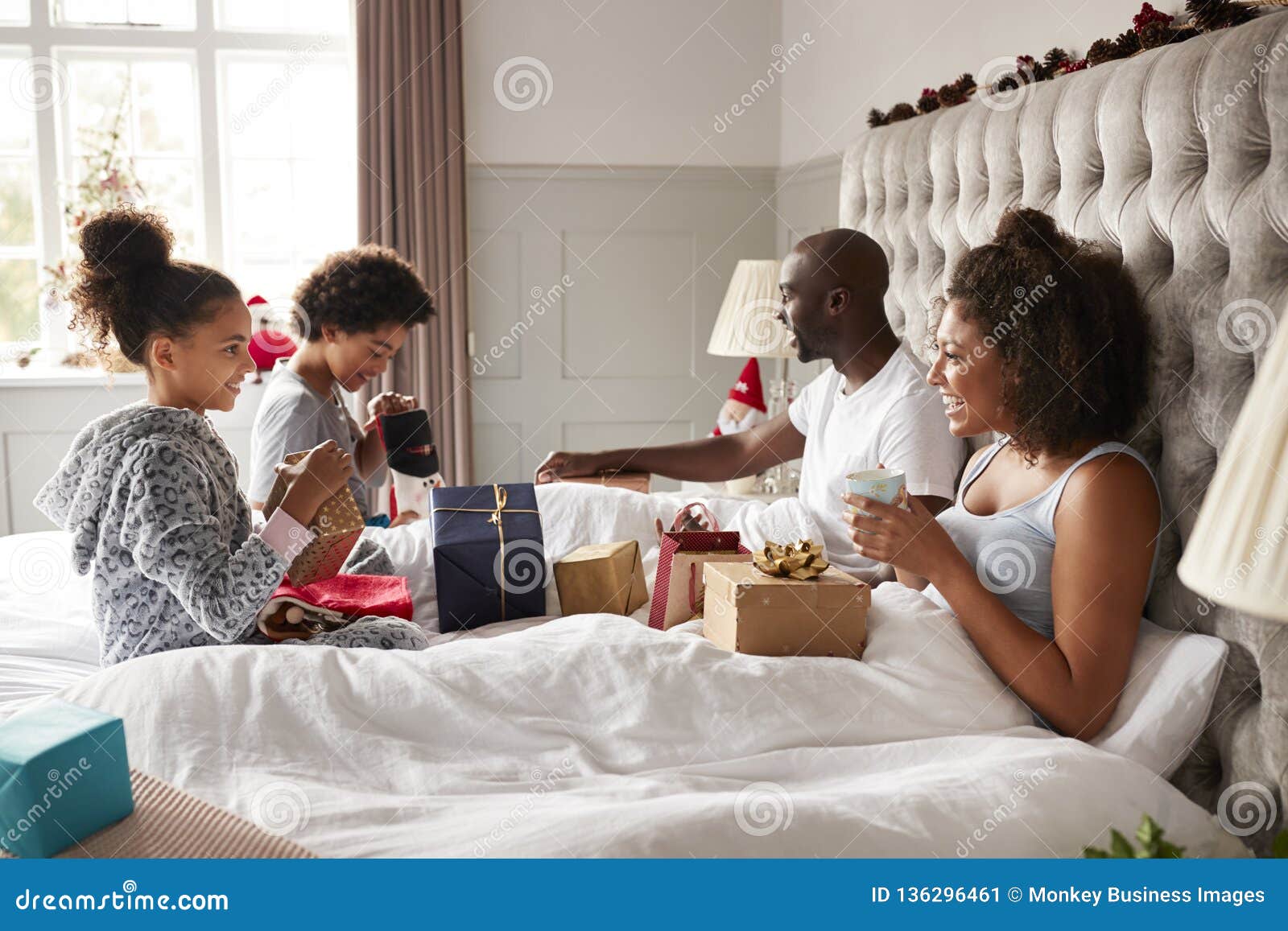 Young Kids Opening Gifts on Parentsï¿½ Bed on Christmas Morning while ...