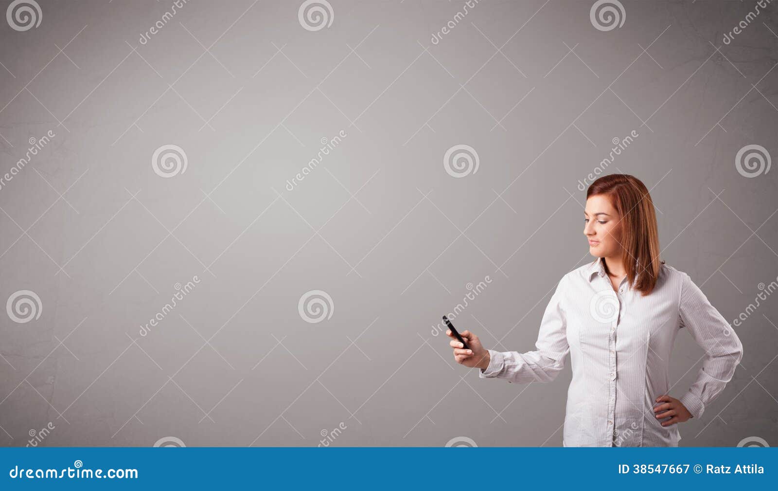 Attractive young lady standing and holding a phone with copy space