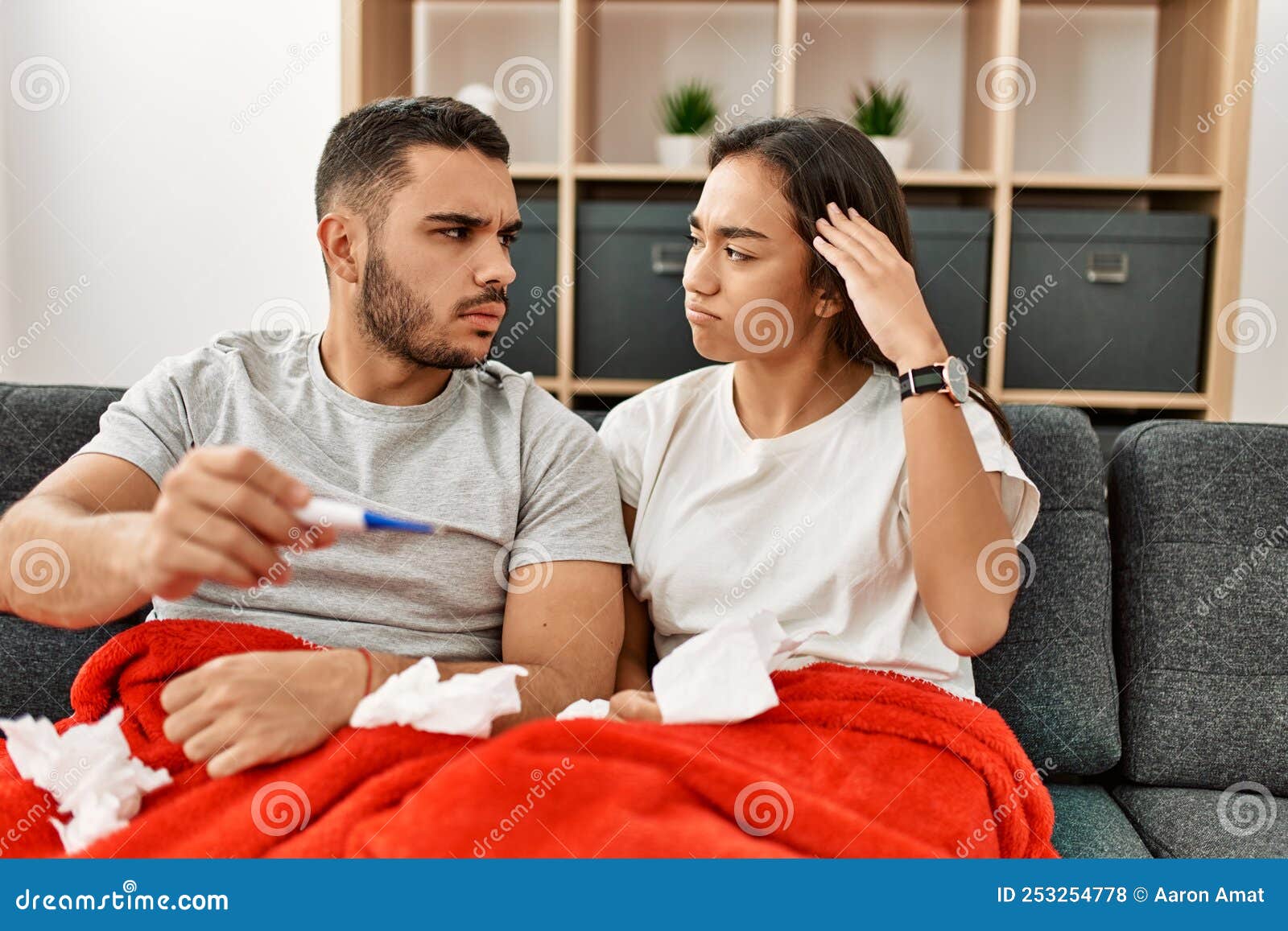 Young Latin Ill Couple Measuring Temperature Using Thermometer at Home