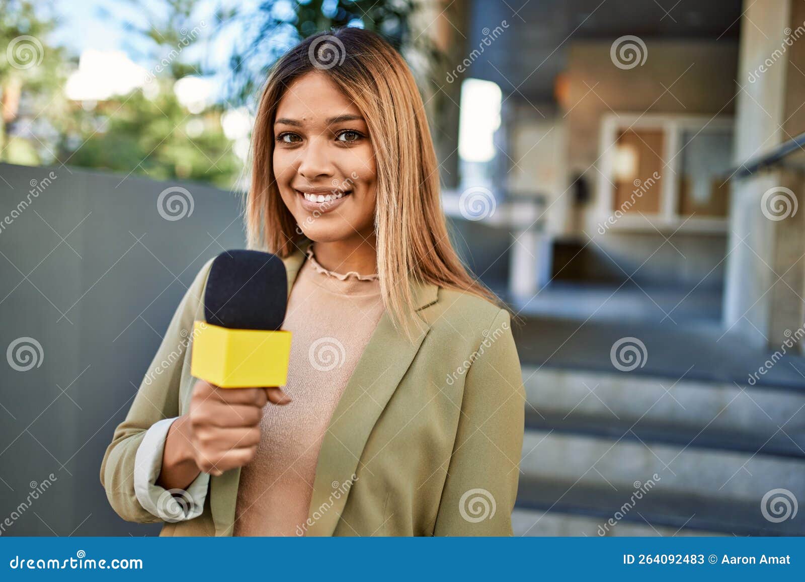 Young Latin Woman Smiling Confident Using Microphone at Street Stock