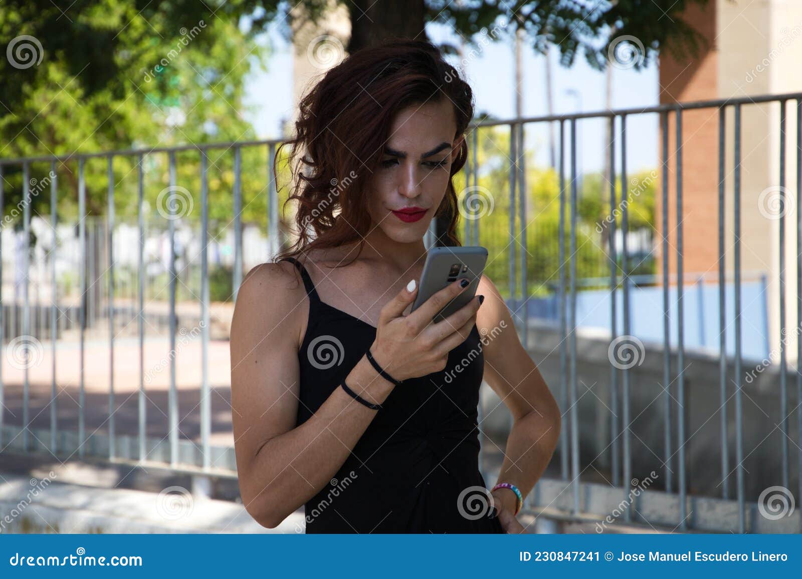 Young Latina and Transsexual Woman is in a Park Talking on a Mobile