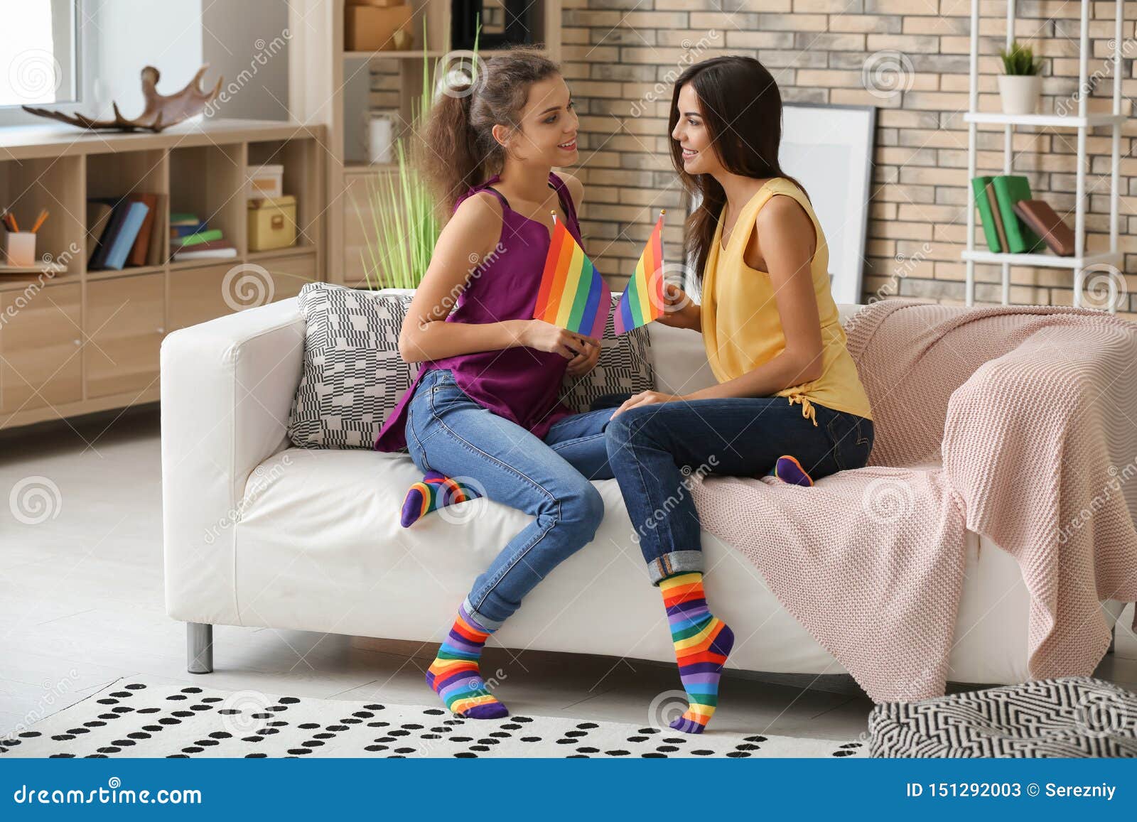 Young Lesbian Couple With Rainbow Flags At Home St