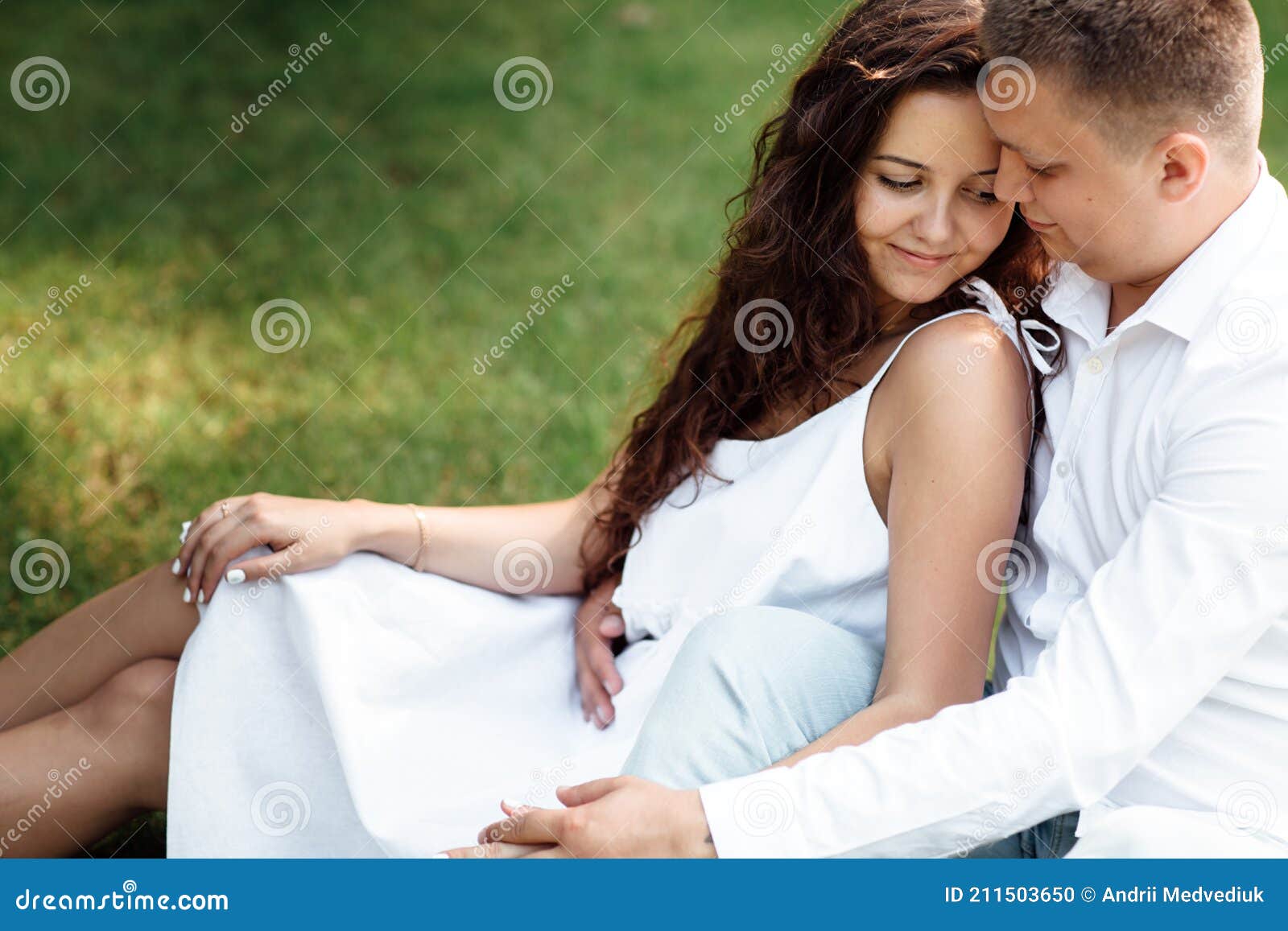 Young Loving Couple is Sitting on Grass in the Park, Hugging