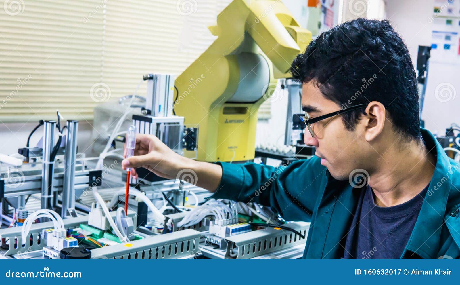 A Young Malay Engineering Student with Spectacles Working in the Lab