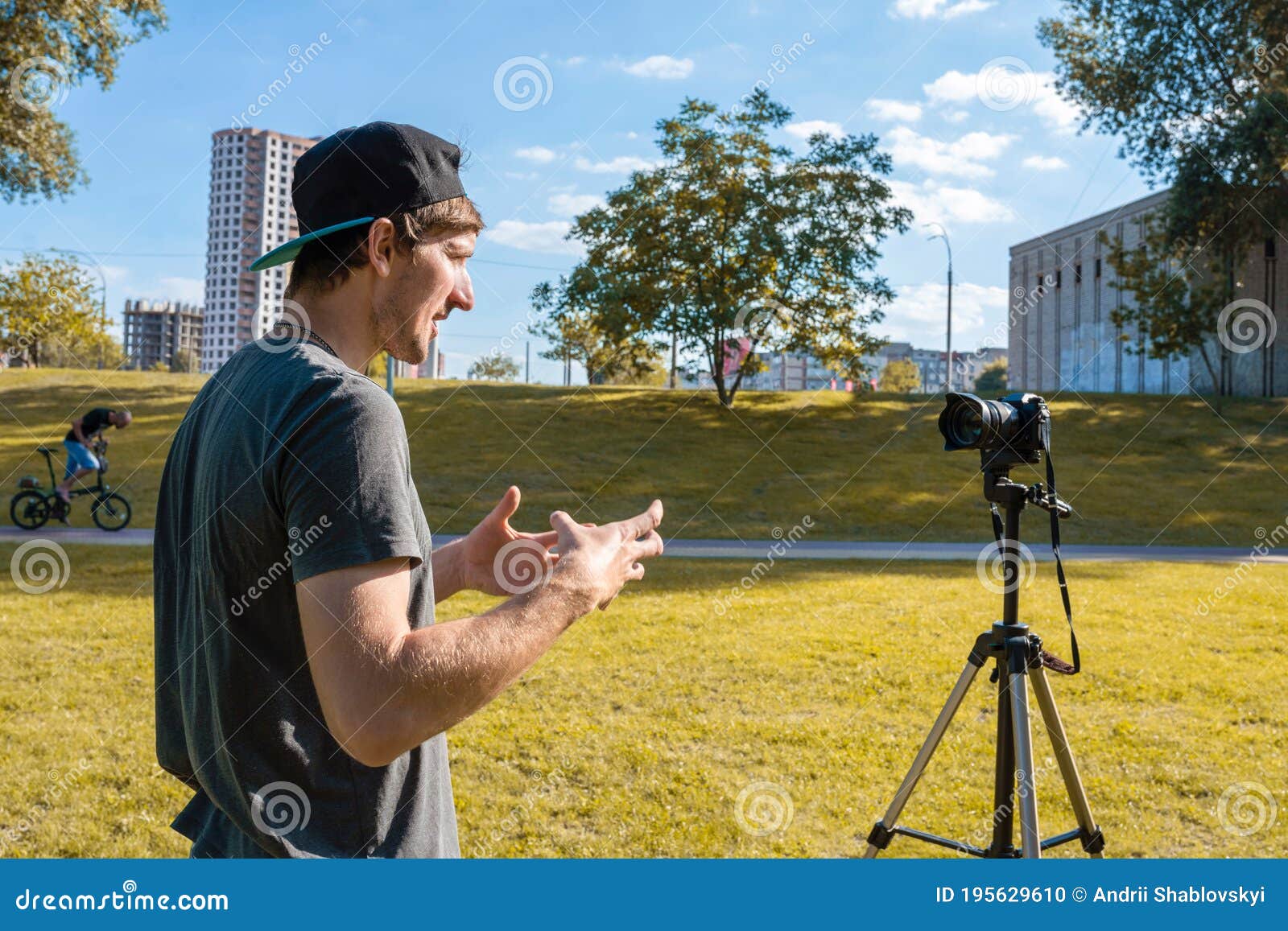 young male blogger recording vlogging on a digital camera in the park on a sunny day. educational videos, lifestyle